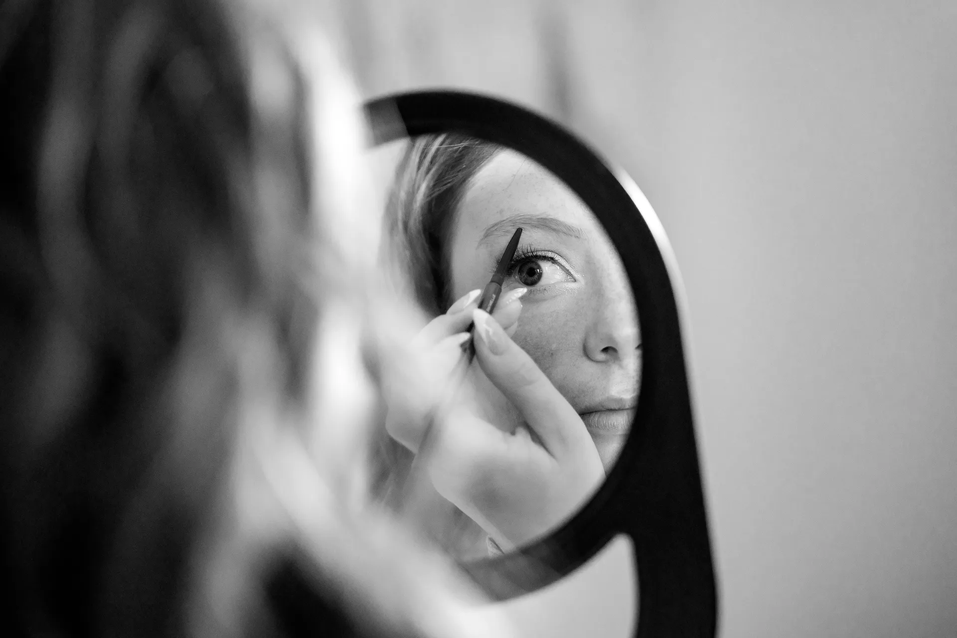 A bride applies makeup while looking in a mirror as she gets ready for a wedding at the York Harbor Reading Room in York, Maine.
