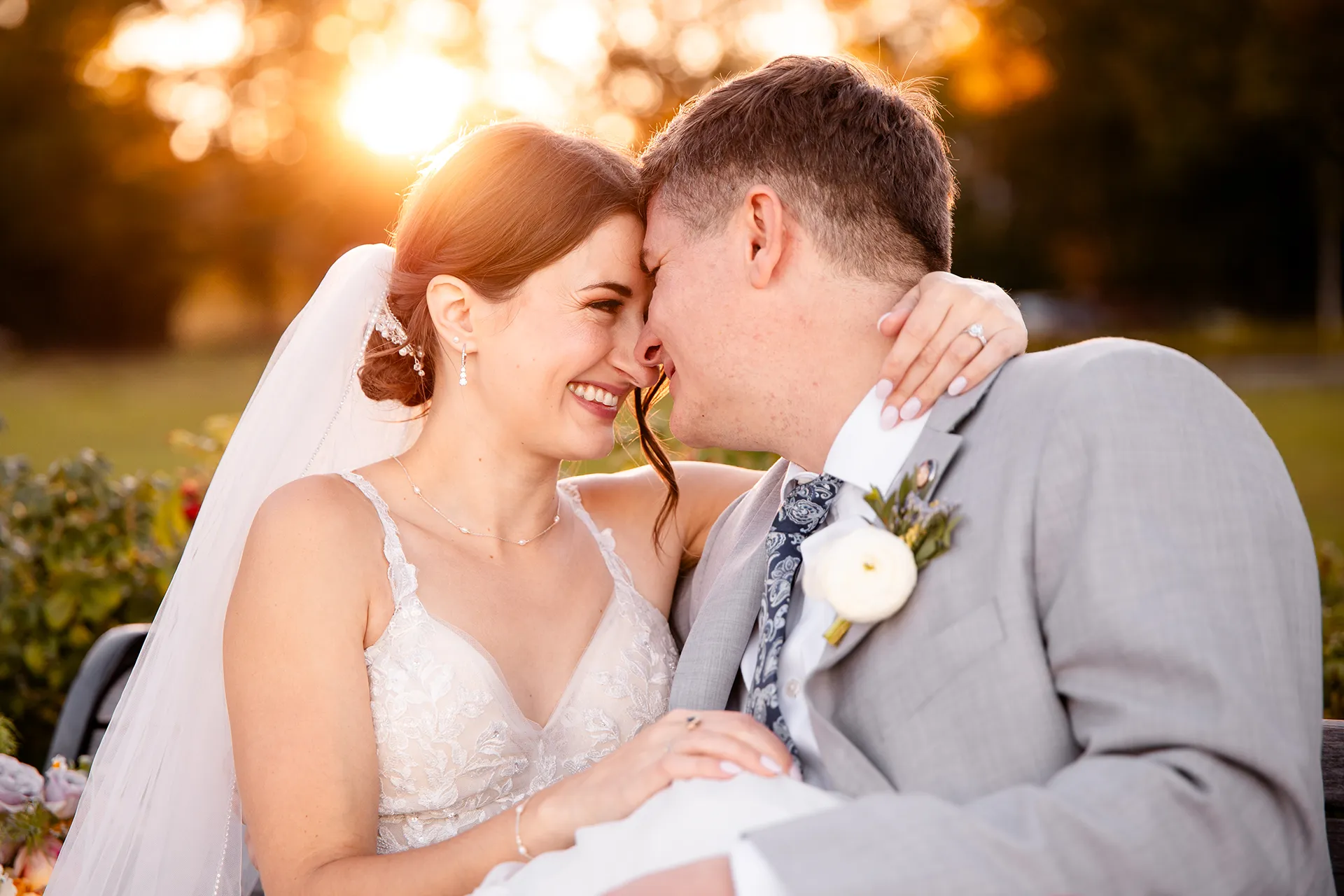A bride and groom smile at each other as the sunsets behind them during wedding portraits at the Bar Harbor Inn and Spa in Bar Harbor, Maine.