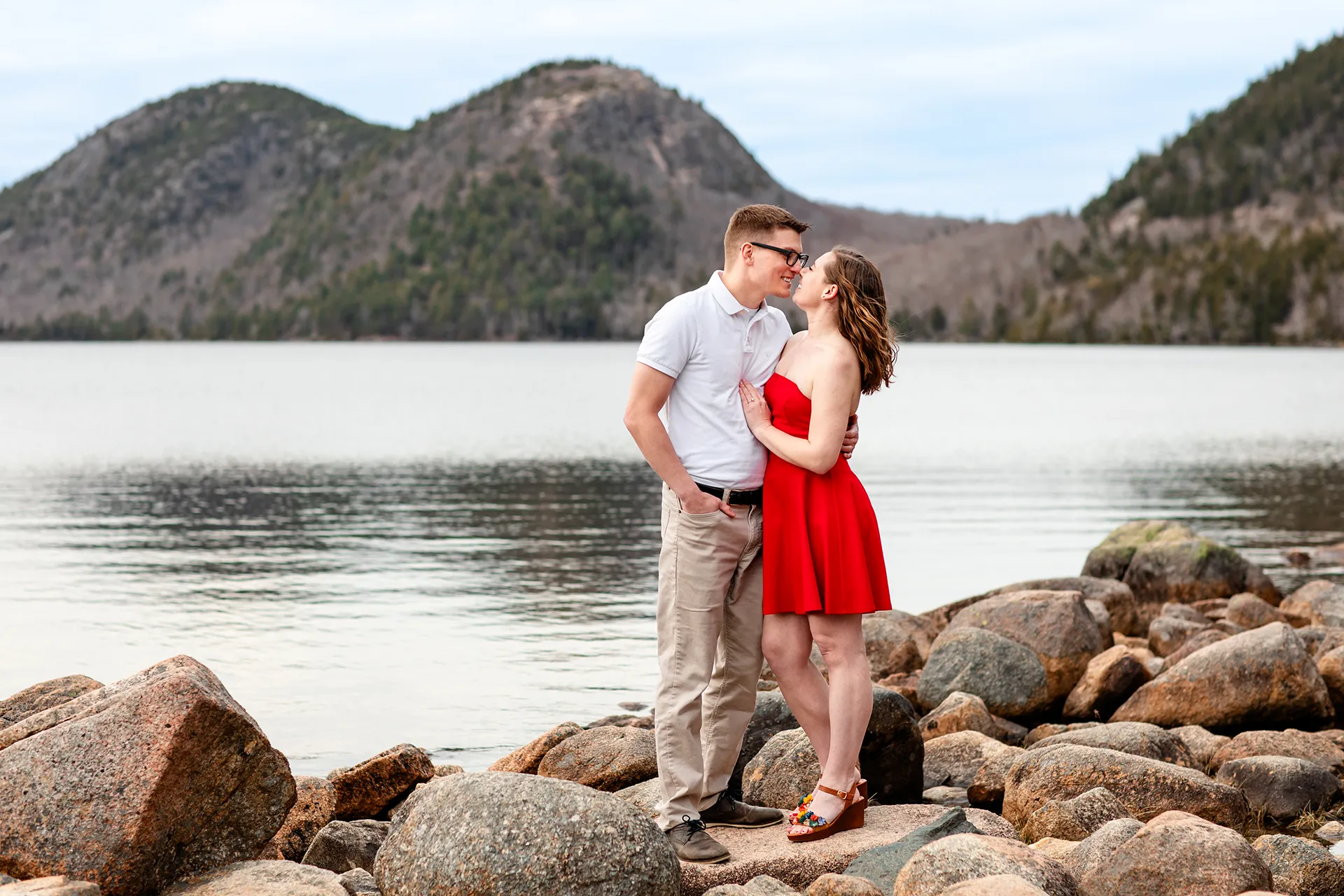 maine engagement photography chelsea mike 09 An engaged couple stand on a rock and rub noses during an engagement session at Jordan Pond in Acadia National Park, Maine.