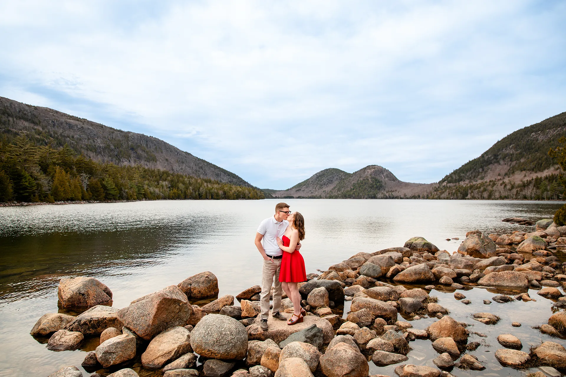 maine engagement photography chelsea mike 11 An engaged couple kiss while standing on a rock during an engagement session at Jordan Pond in Acadia National Park, Maine.