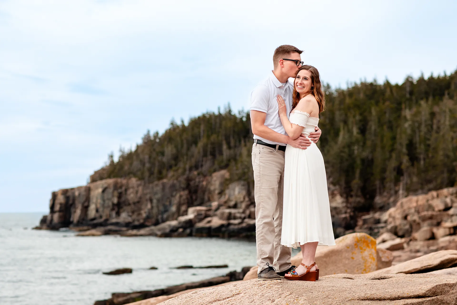 maine engagement photography chelsea mike 13 A man kisses a smiling woman on the head during an engagement session near Otter Cliff in Acadia National Park, Maine.