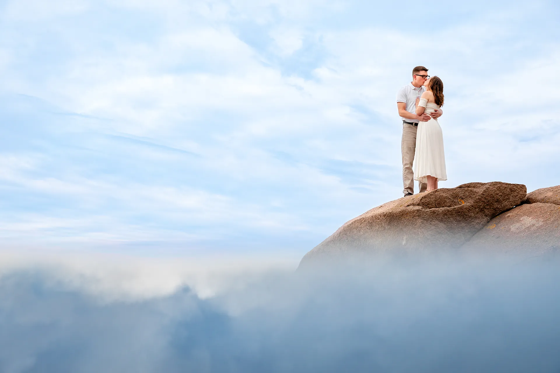 maine engagement photography chelsea mike 14 An engaged couple kisses on a rock surrounded by blue and purple clouds during an engagement session in Acadia National Park, Maine.