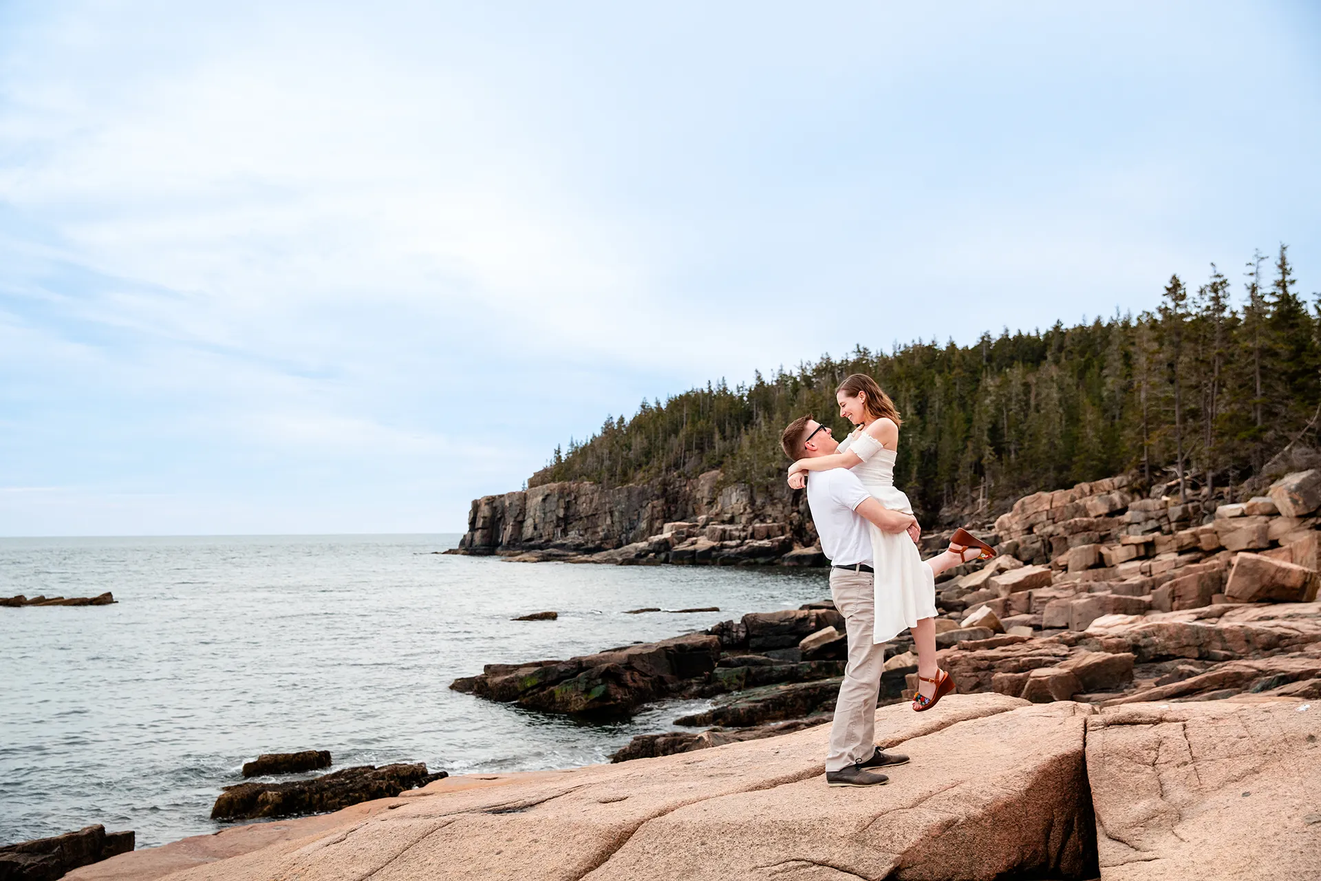 maine engagement photography chelsea mike 17 A man lifts a woman during an engagement session near Otter Cliff in Acadia National Park, Maine.