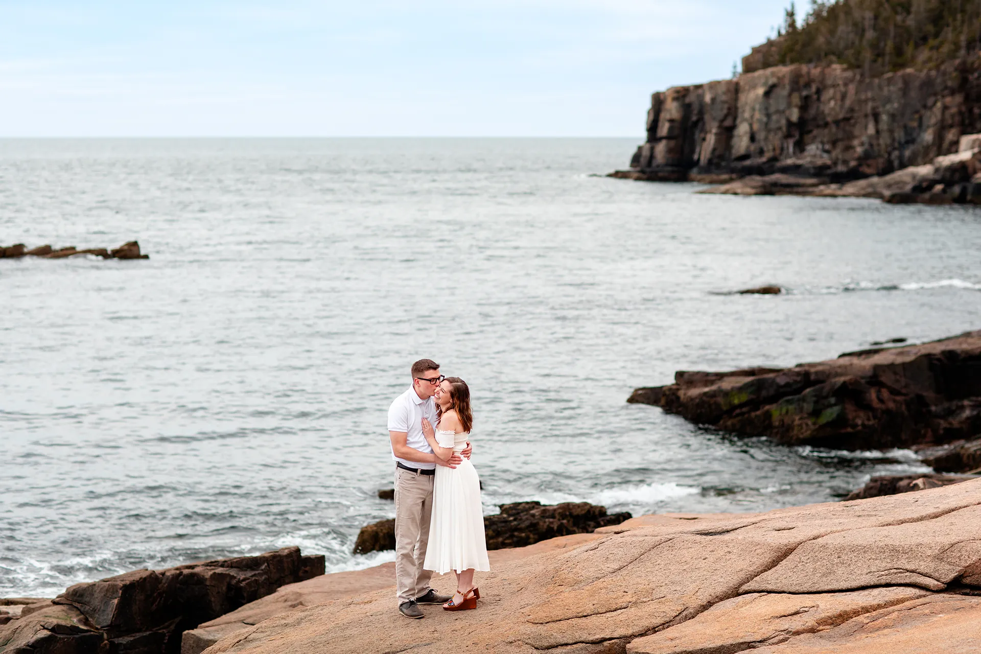 maine engagement photography chelsea mike 19 A man kisses a woman on the cheek during an engagement session near Otter Cliff in Acadia National Park, Maine.