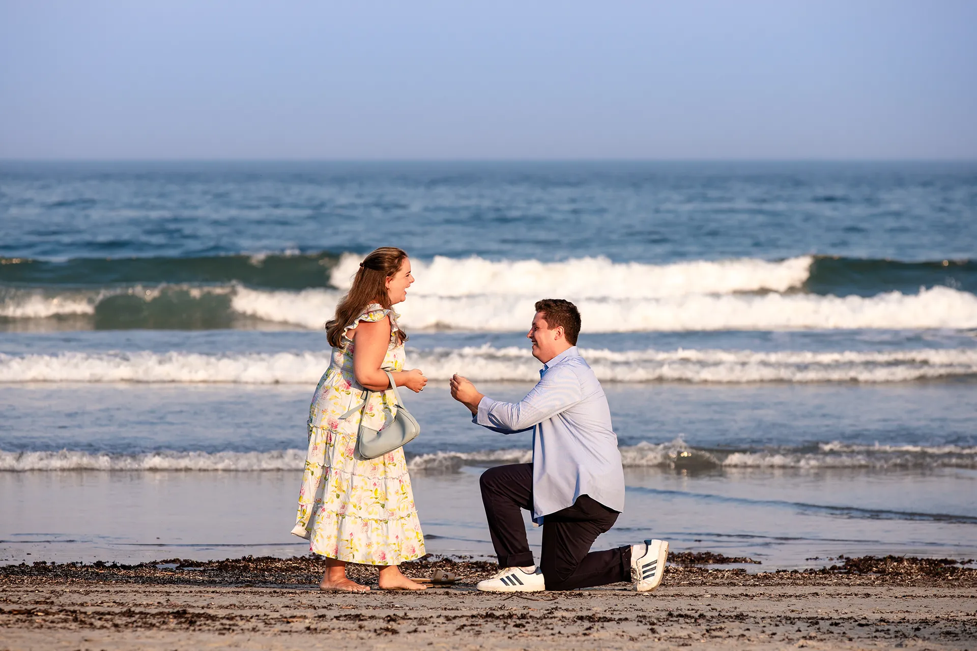 A man kneels down on one knee as he proposes to a woman on Long Sands Beach in York, Maine.