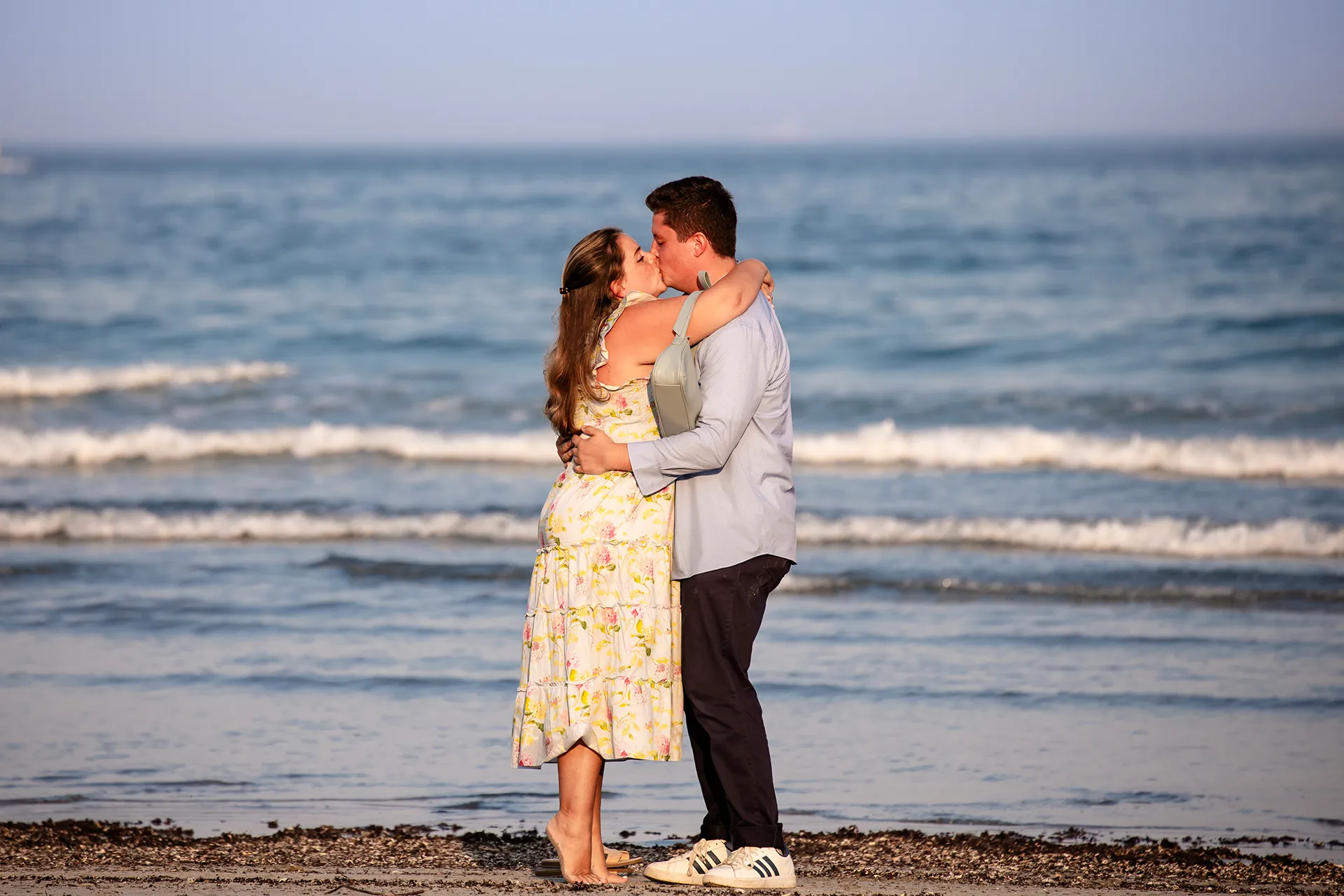 A man and woman kiss after getting engaged on Long Sands Beach in York, Maine.