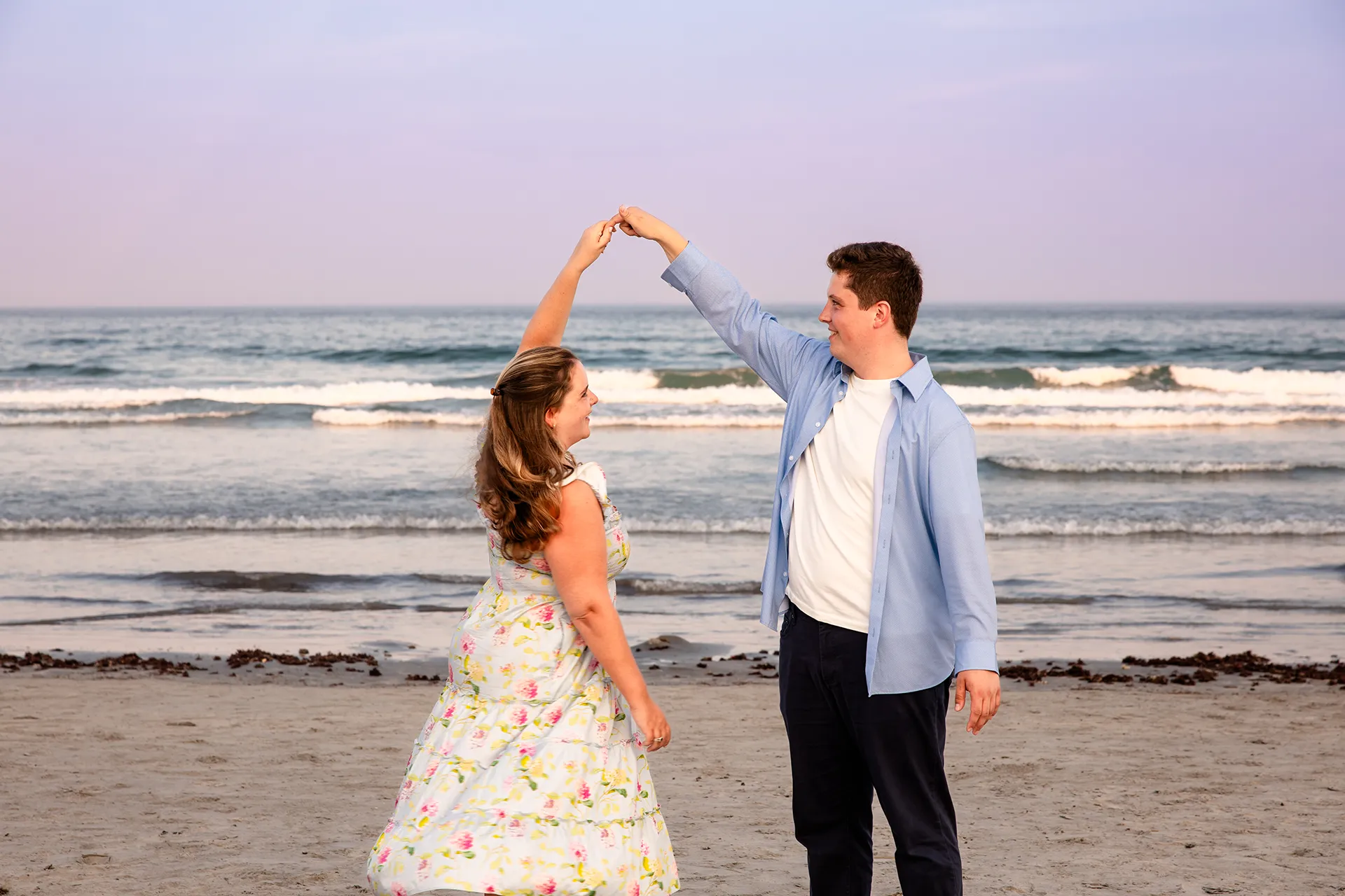 A man spins a woman during engagement portraits on Long Sands Beach in York, Maine.