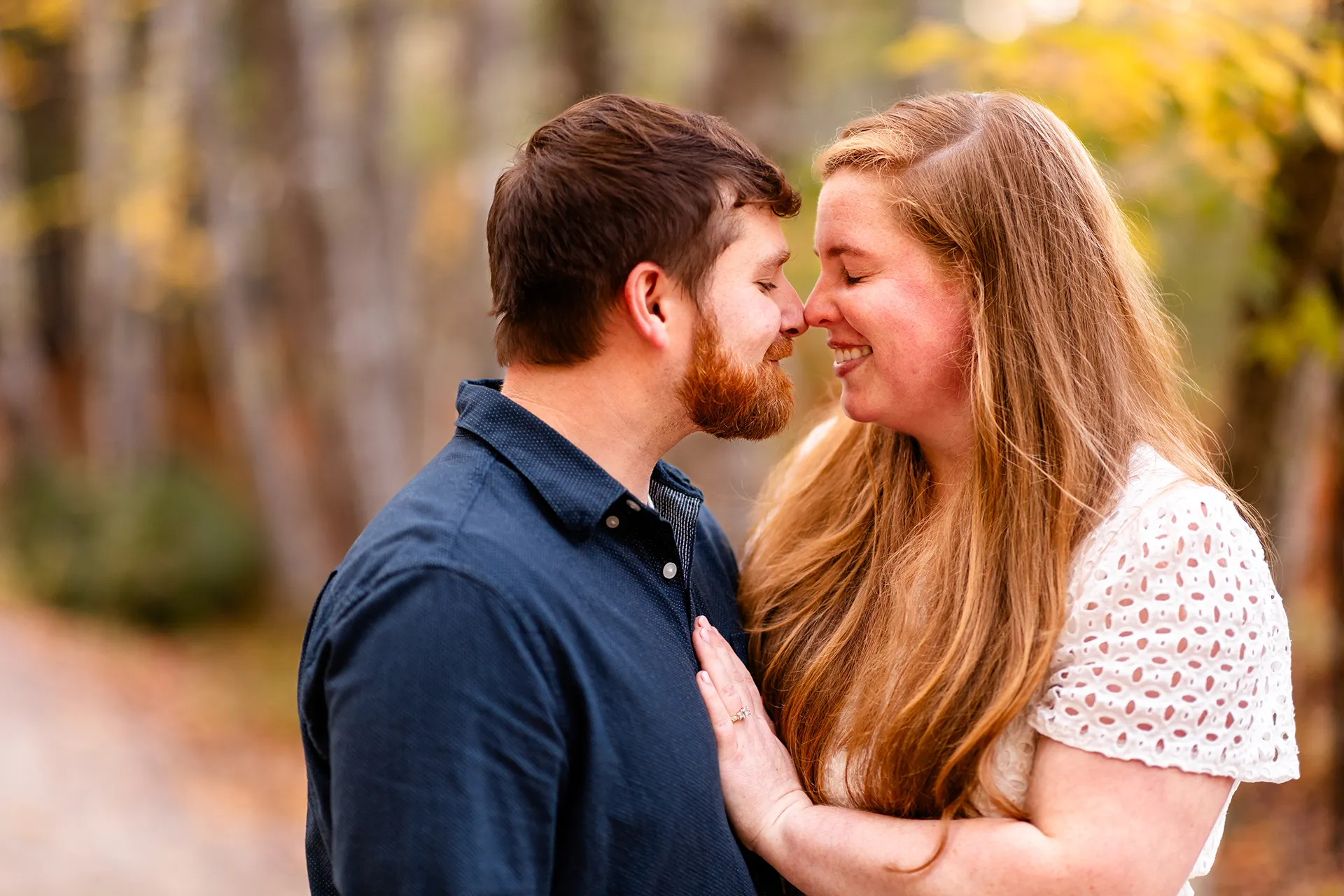 An engaged couple rub noses during a fall engagement session on the Hemlock Trail at Acadia National Park in Bar Harbor, Maine.