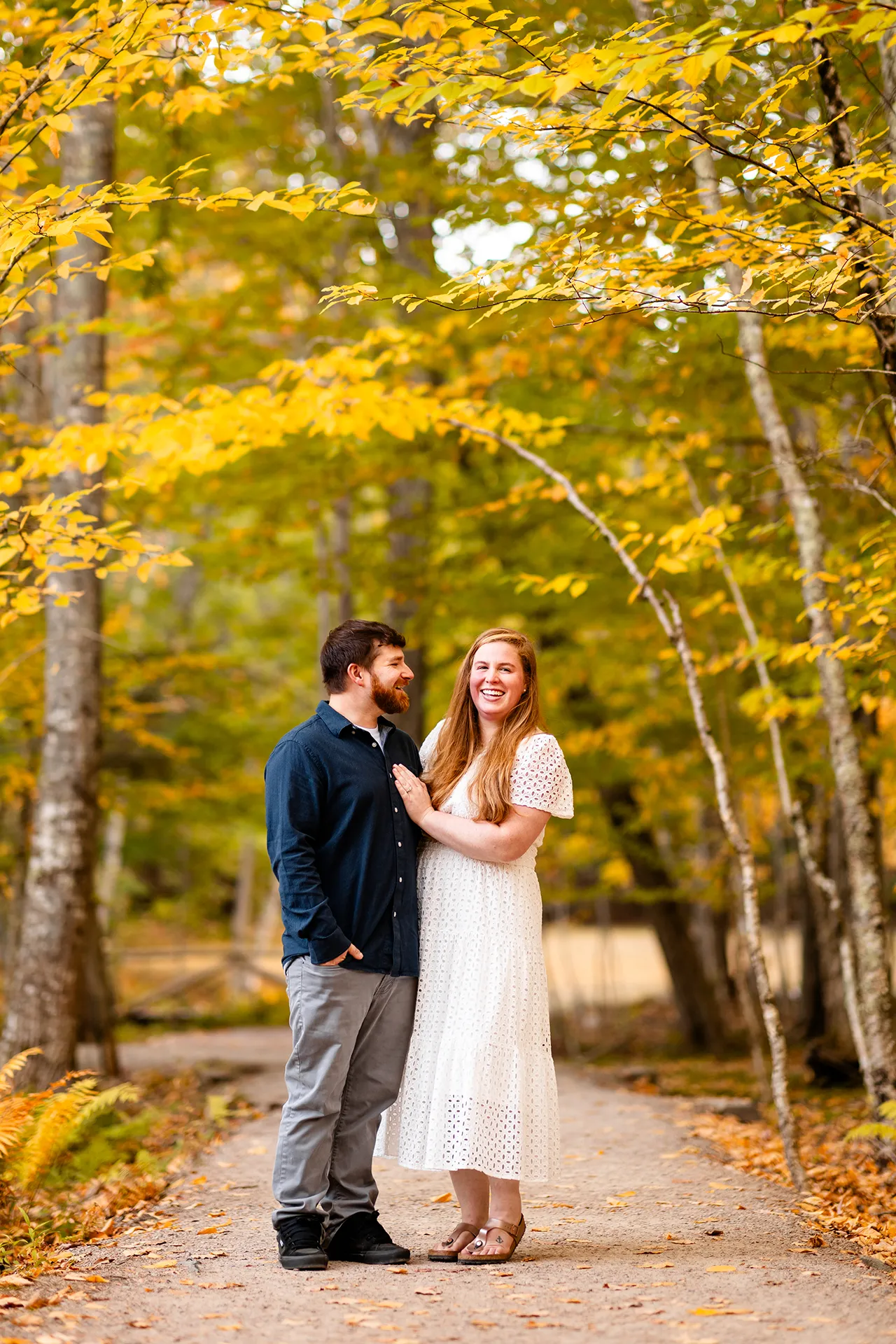 A man and woman laugh during an engagement session near the Wild Gardens of Acadia at Acadia National Park in Bar Harbor, Maine.