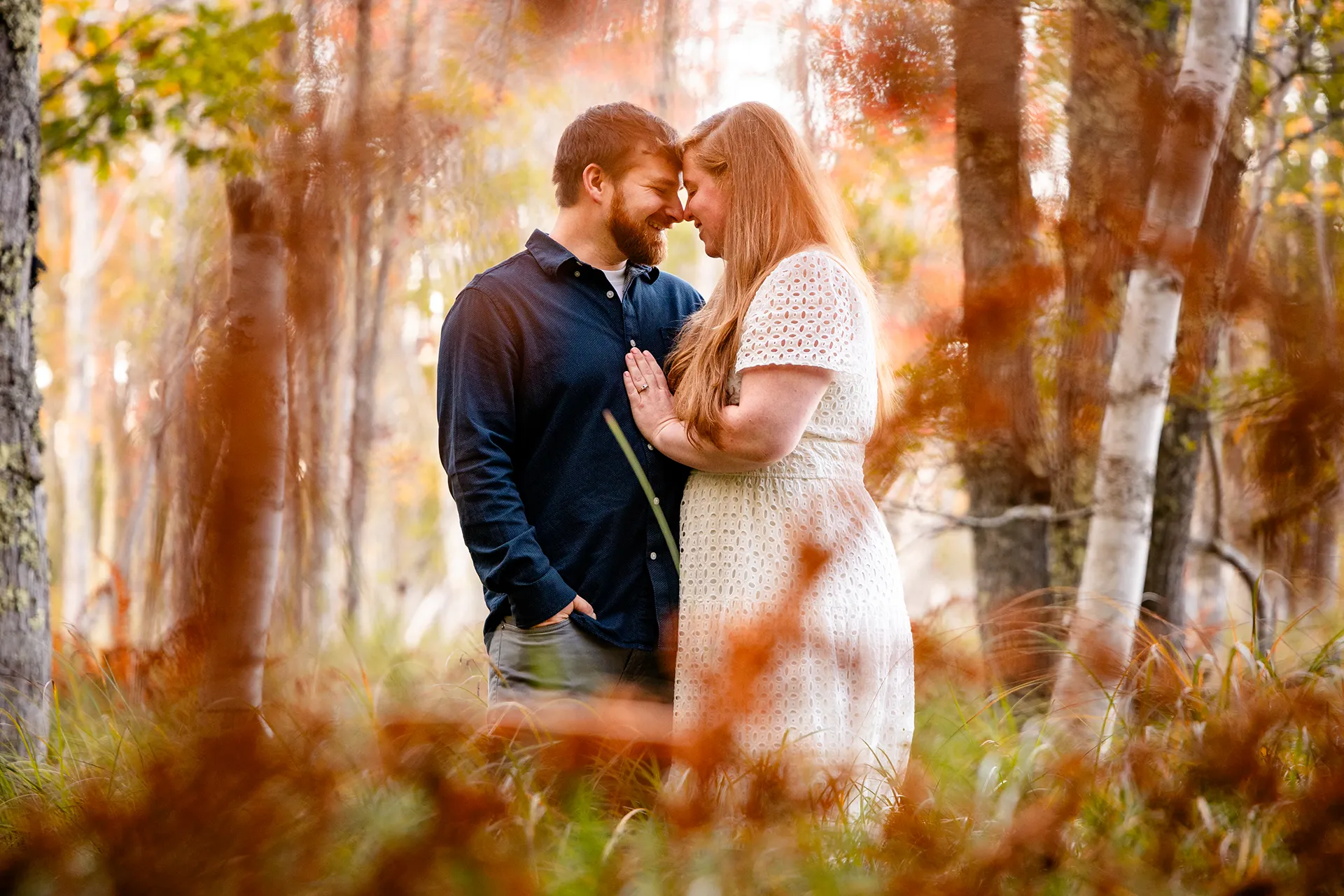 A man and woman smile as they rest their heads together during an engagement session at Acadia National Park in Bar Harbor, Maine.