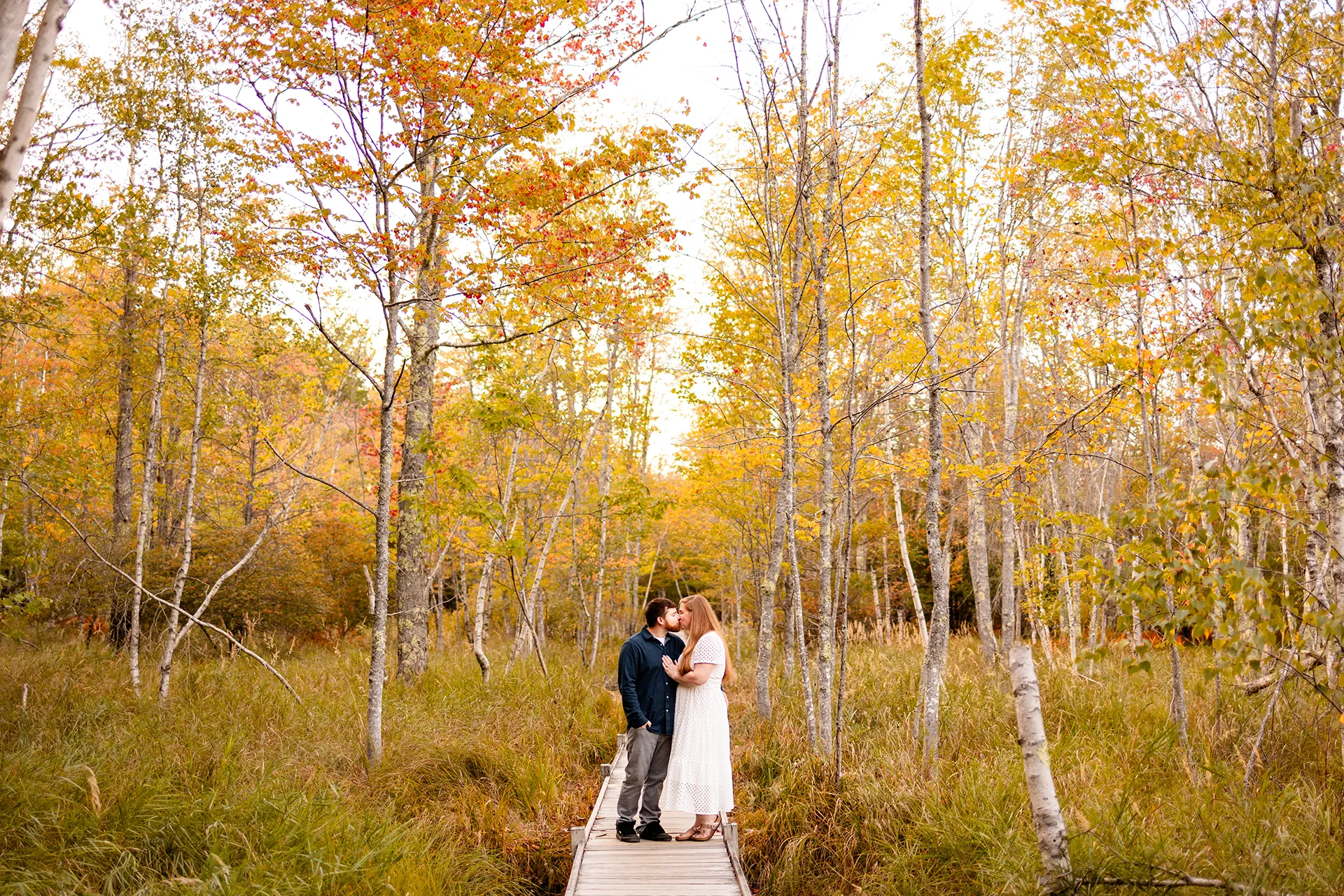 An engaged couple kiss during a fall engagement session on the Jesup Path at Acadia National Park in Bar Harbor, Maine.