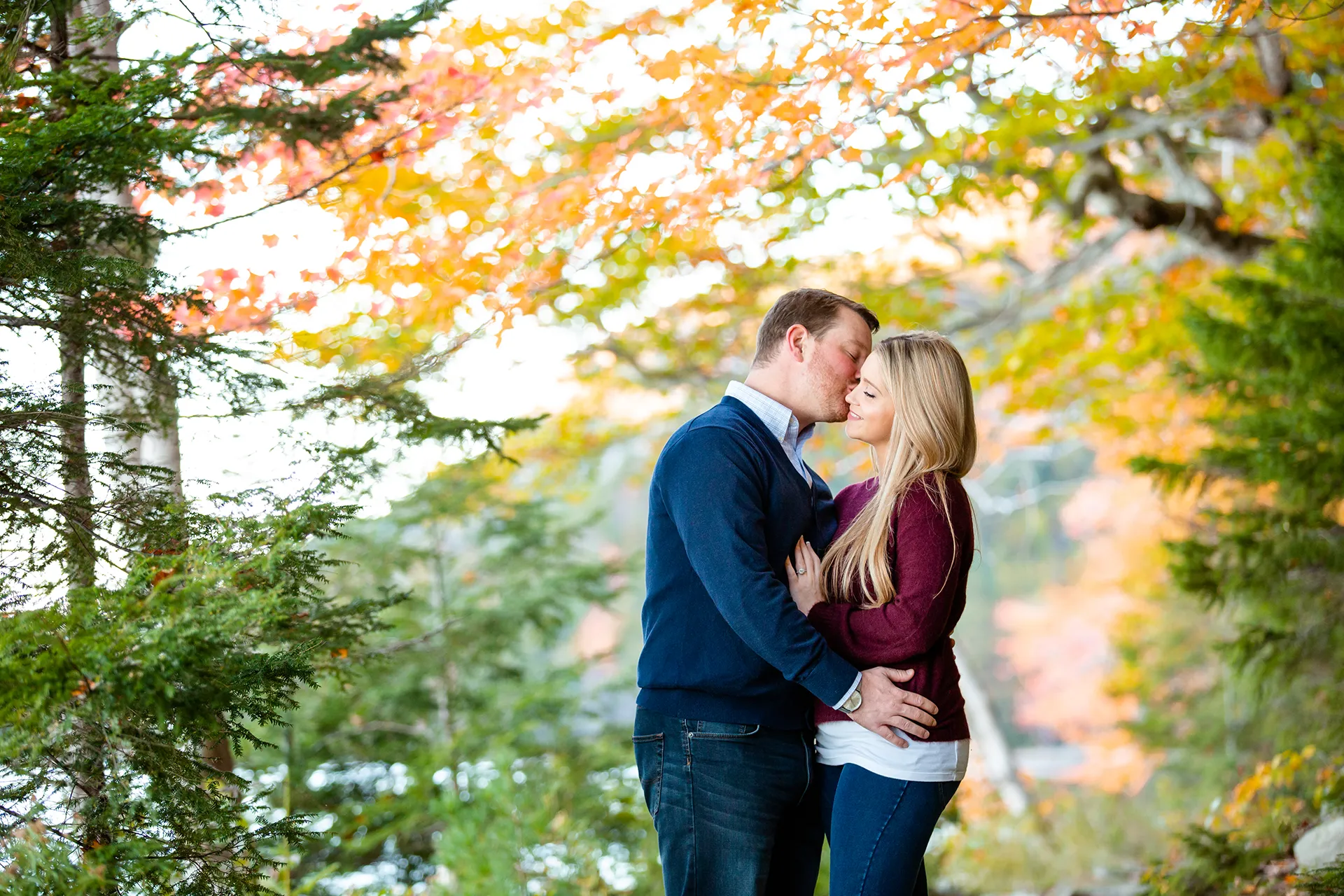 maine engagement photography maryann chris 06 A man kisses a woman on the cheek during a fall engagement session at Jordan Pond in Acadia National Park.