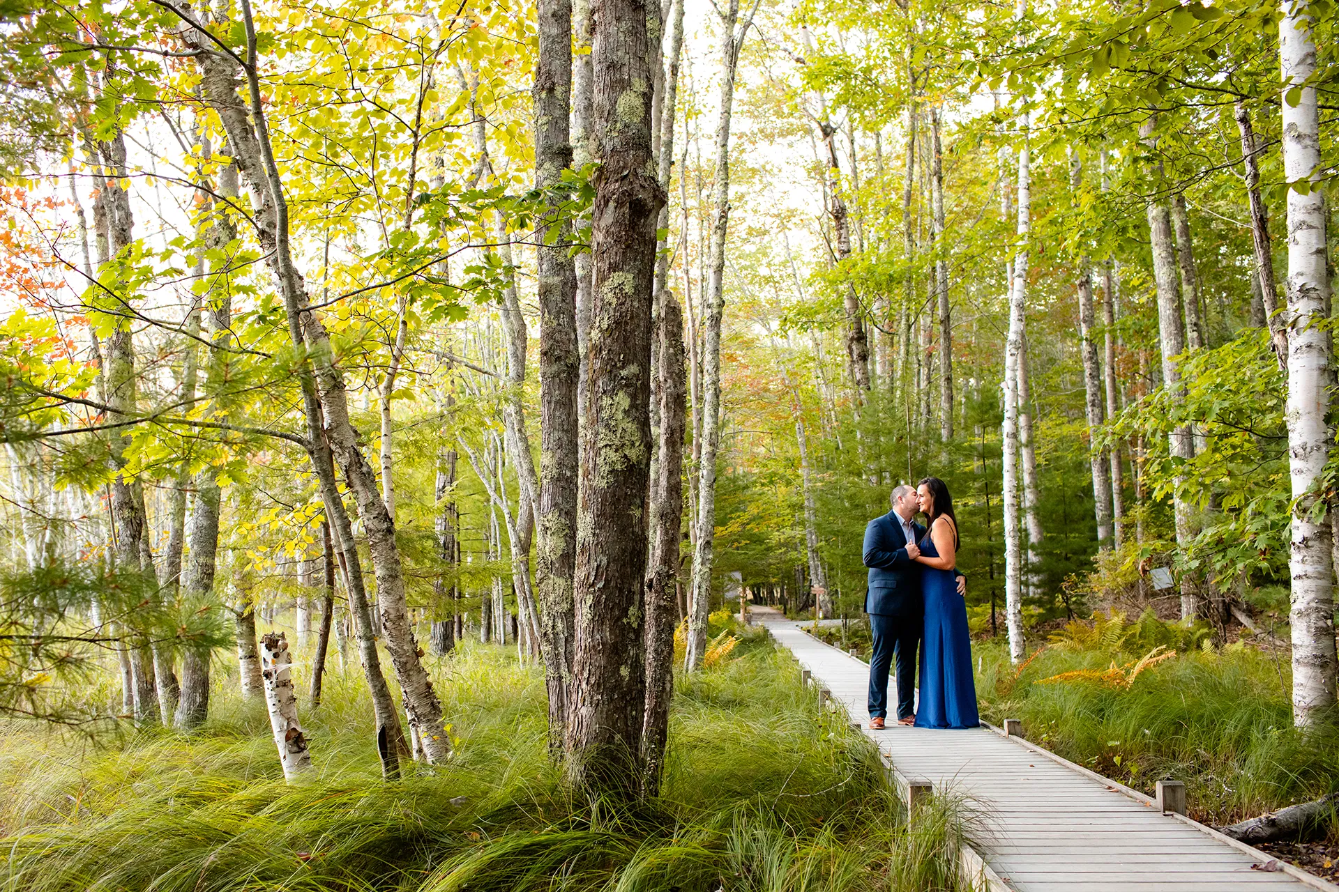 A man kisses a woman on the cheek during a engagement session on the Jesup Path in Acadia National Park, Maine.
