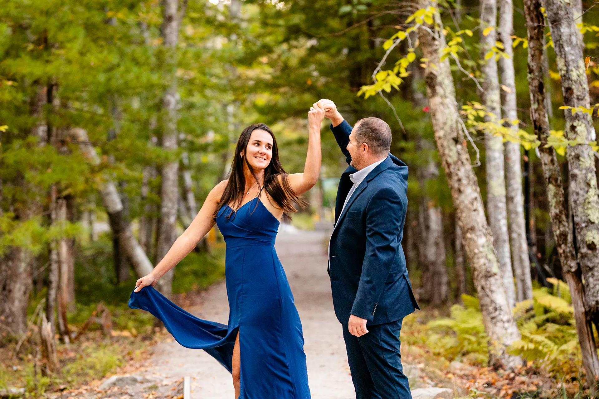 A man spins a woman during a engagement session on the Jesup Path in Acadia National Park, Maine.