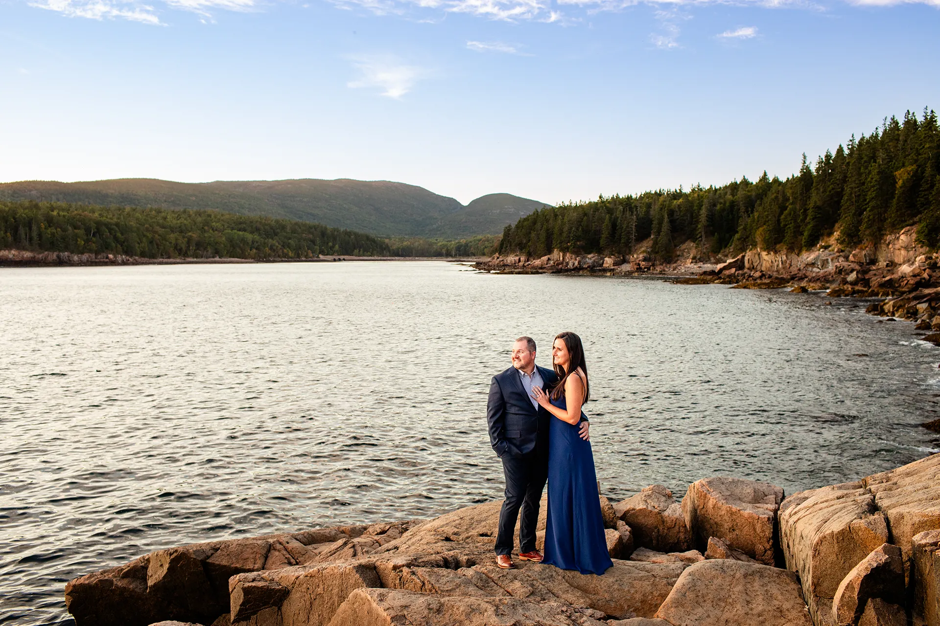 An engaged couple pose on a cliff during an engagement session on Otter Point in Acadia National Park near Bar Harbor, Maine.