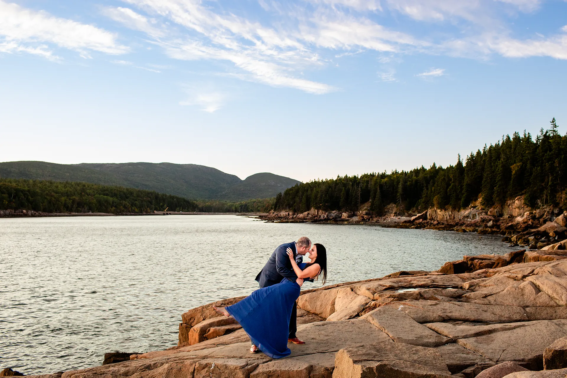 A man dips a woman during an engagement session on Otter Point in Acadia National Park near Bar Harbor, Maine.