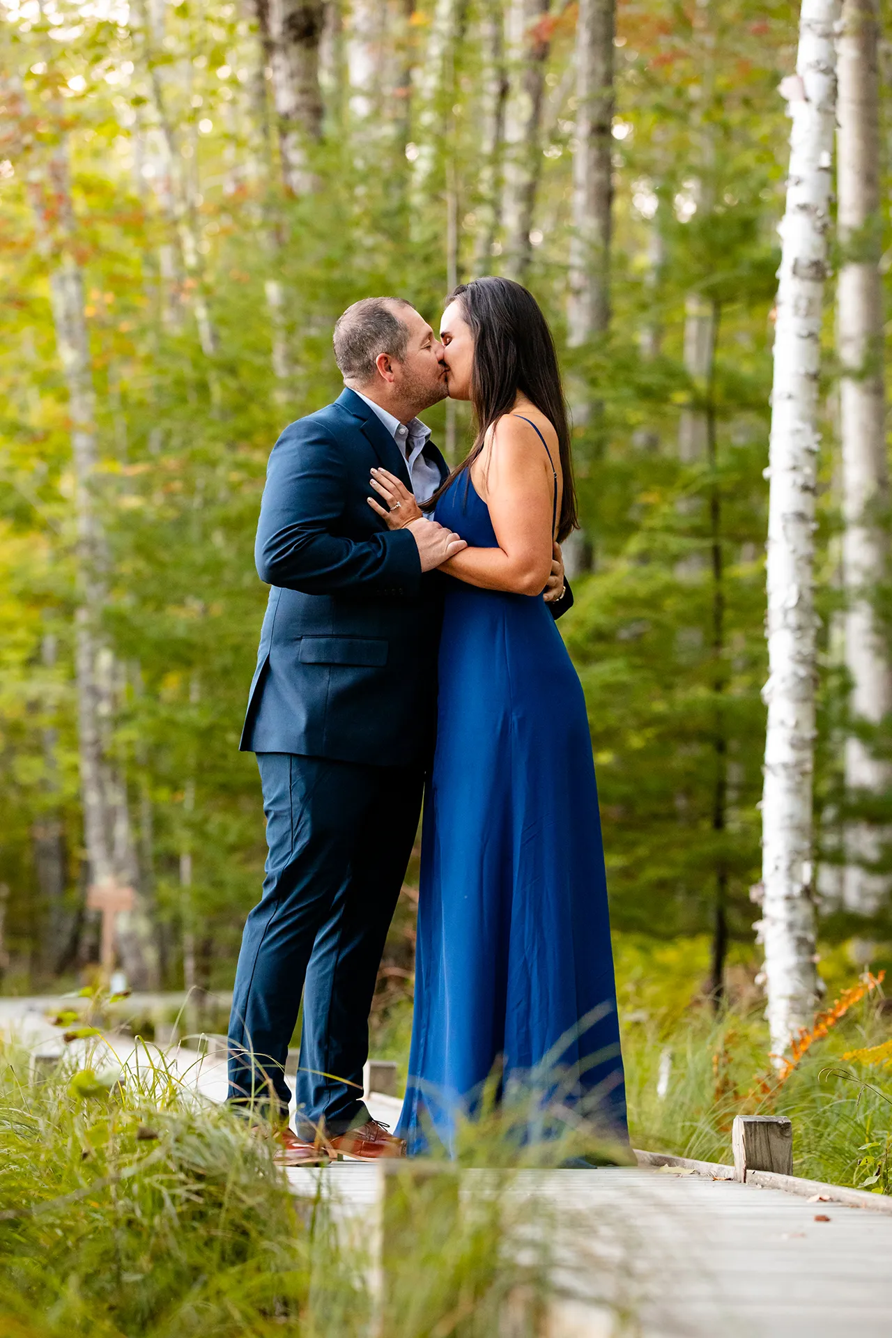 An engaged couple kiss on the Jesup Path during a engagement session near the Wild Gardens of Acadia in Acadia National Park, Maine.