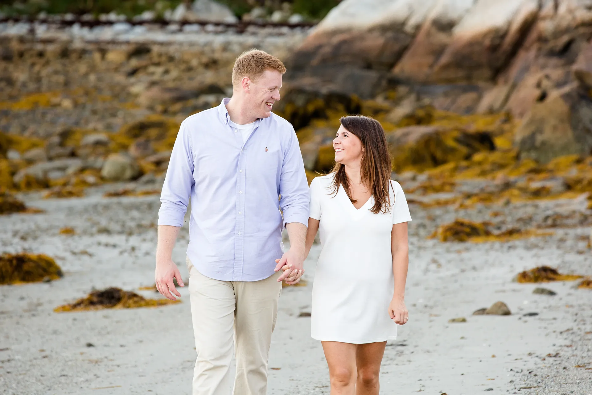 maine engagement photography stephanie nick 07 An engaged couple smile at each other as they walk on a beach during an engagement session at Curtis Cove in Blue Hill, Maine.