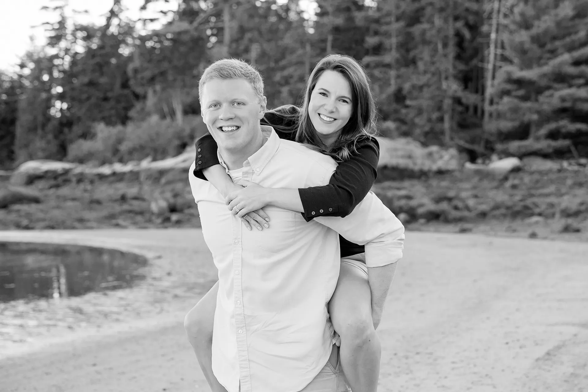 maine engagement photography stephanie nick 10 A man gives a woman a piggy back ride as they smile during an engagement session at Curtis Cove Beach in Blue Hill, Maine.