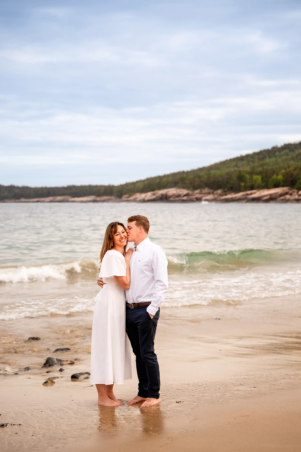 A man kisses a woman on the cheek during an engagement session at Sand Beach in Acadia National Park near Bar Harbor, Maine.