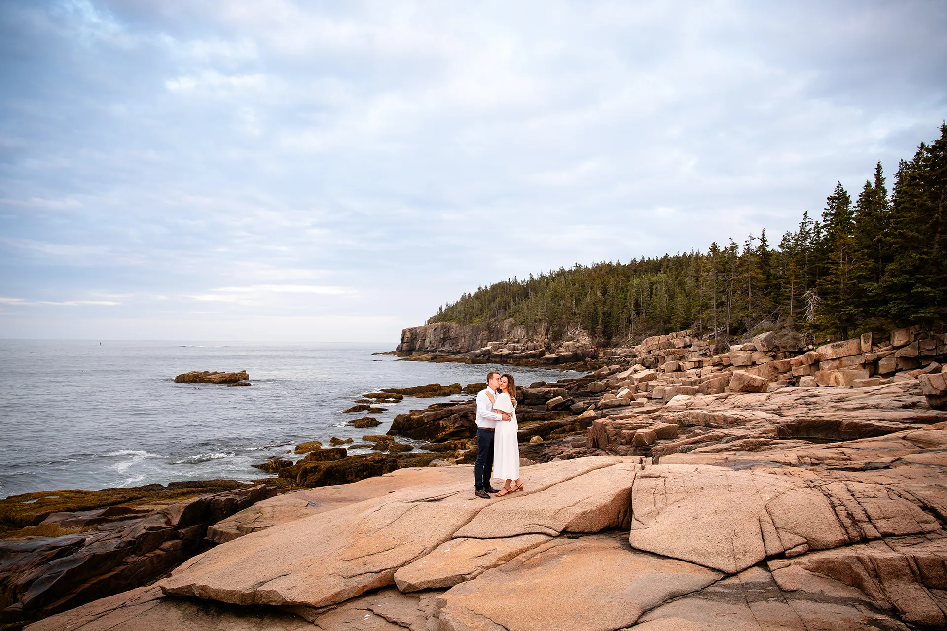 A man kisses a woman on the cheek during an engagement session near Otter Cliff in Acadia National Park near Bar Harbor, Maine.