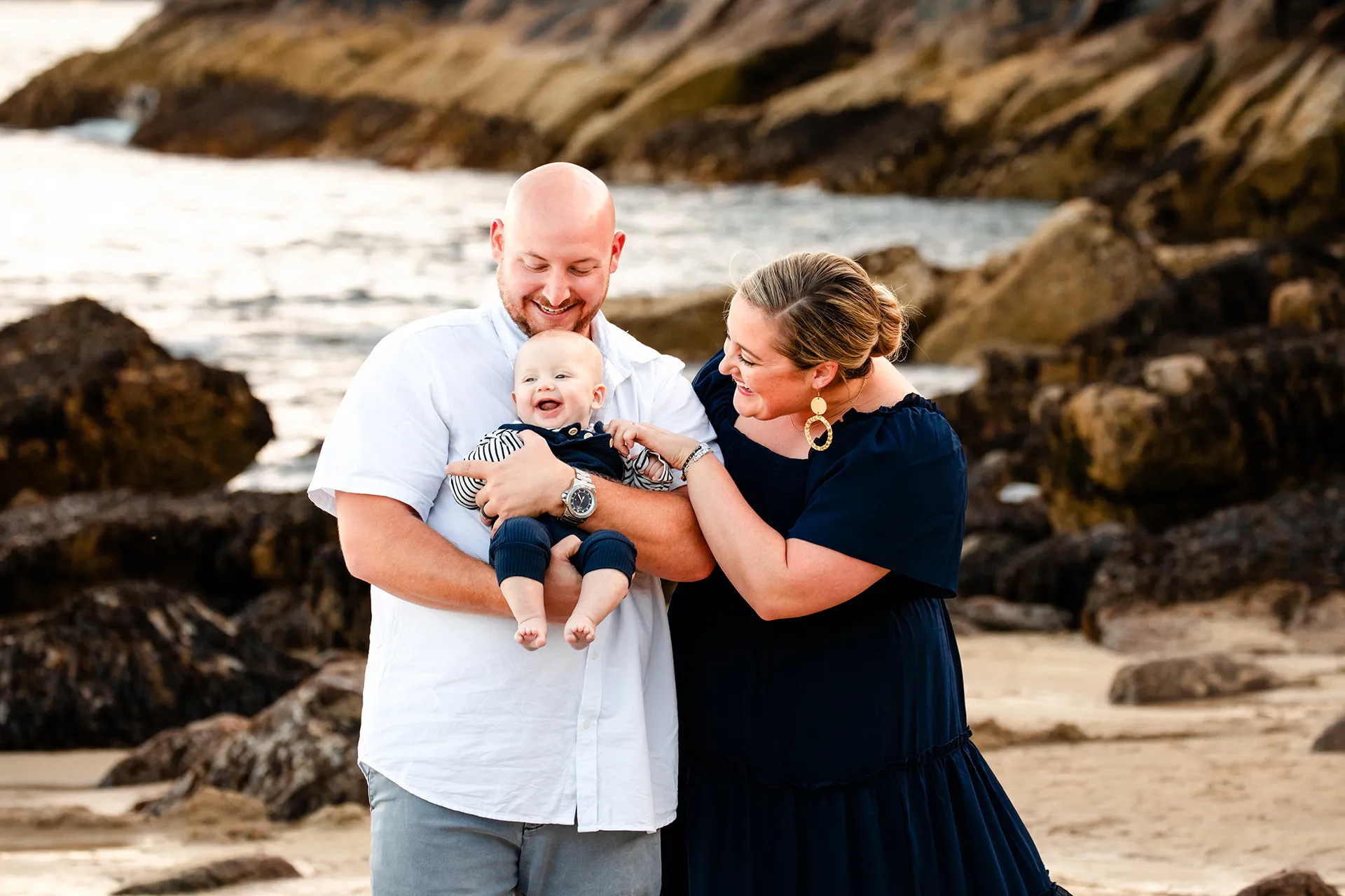 maine family photography daehler 02 A mom and dad snuggle their son during a family portrait session on Sand Beach in Acadia National Park near Bar Harbor, Maine.