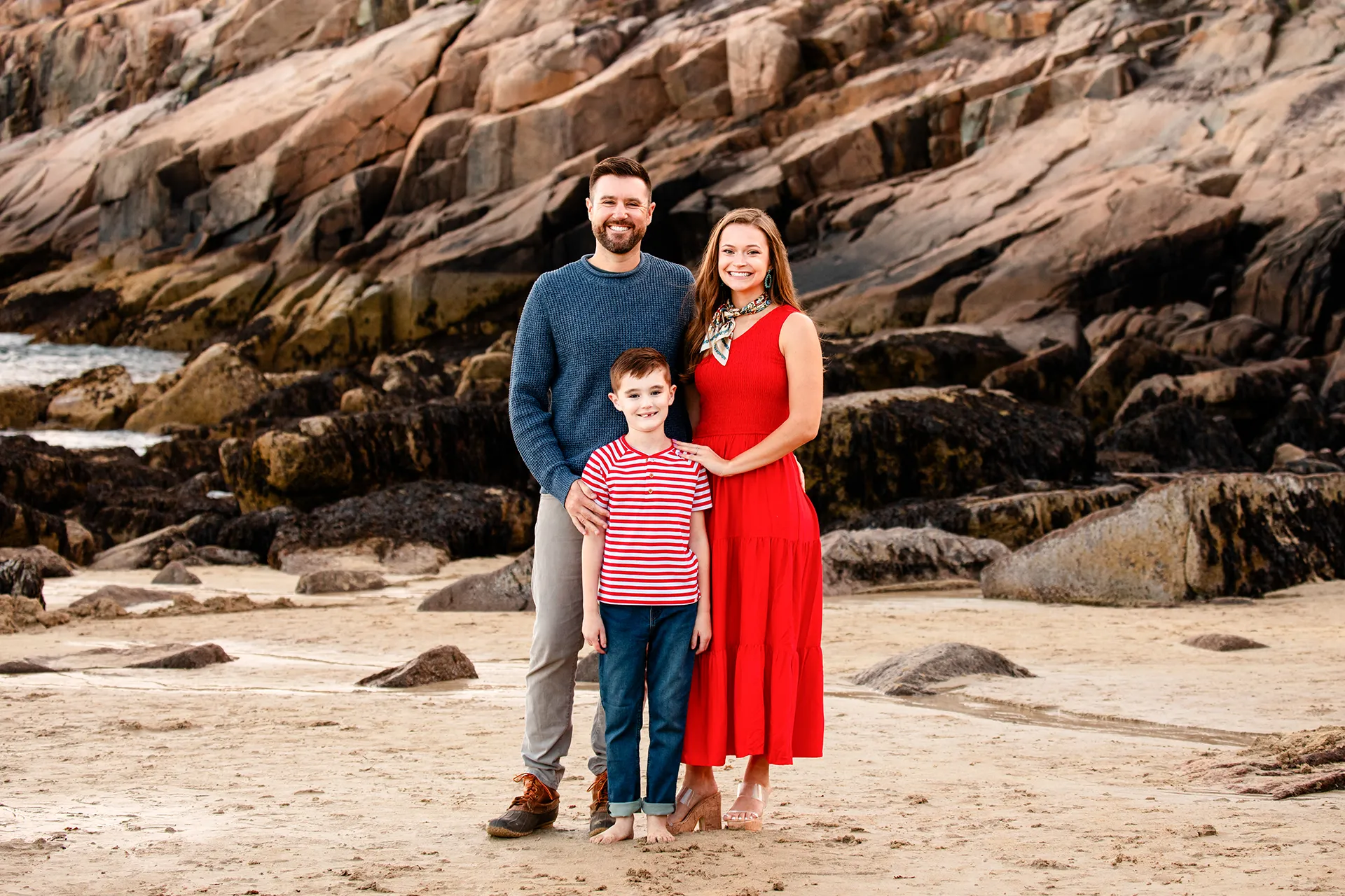 maine family photography daehler 05 A mom and dad smile and pose with their son during a family portrait session on Sand Beach in Acadia National Park near Bar Harbor, Maine.