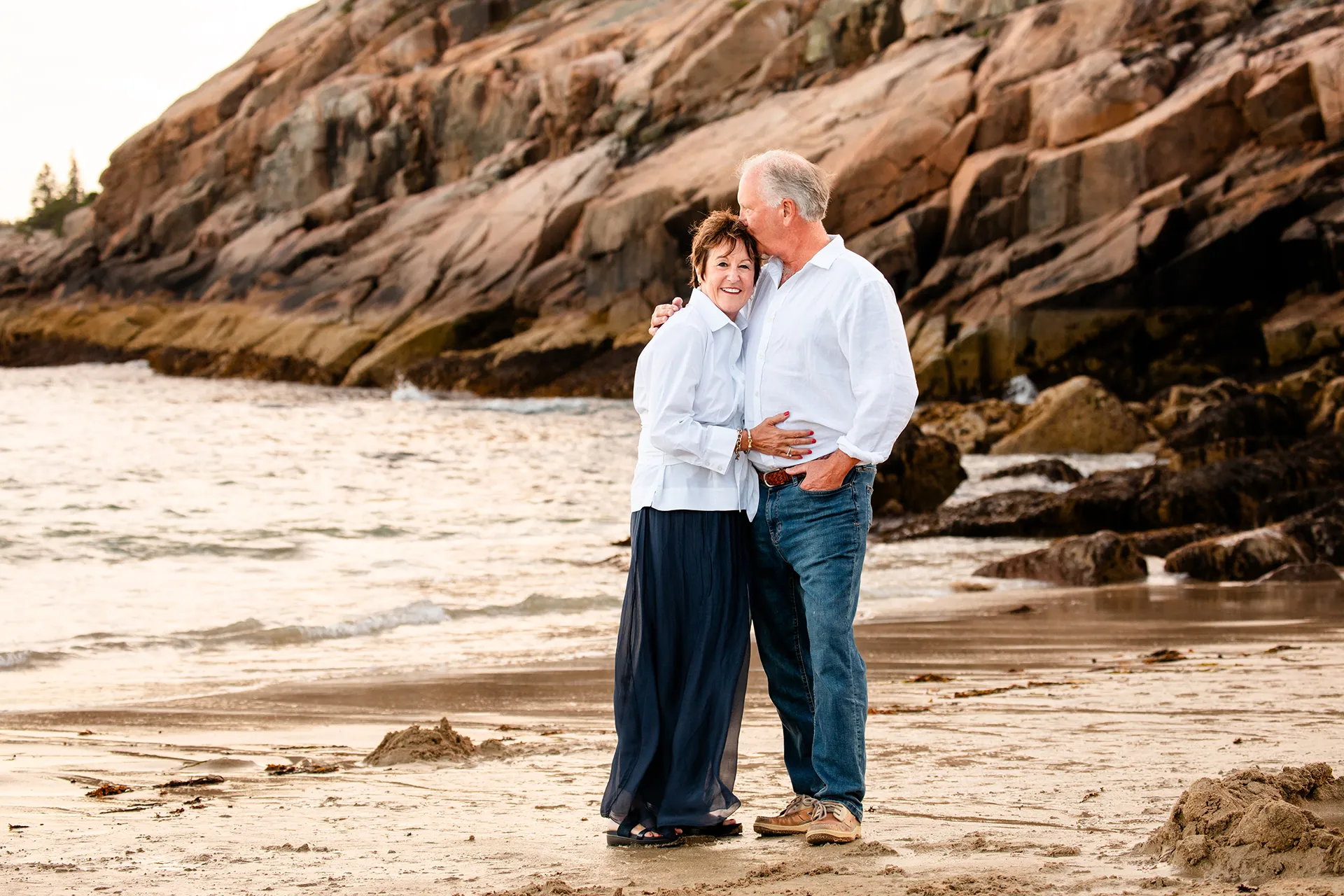 maine family photography daehler 09 A man kisses a woman on the head during a family portrait session on Sand Beach in Acadia National Park near Bar Harbor, Maine.