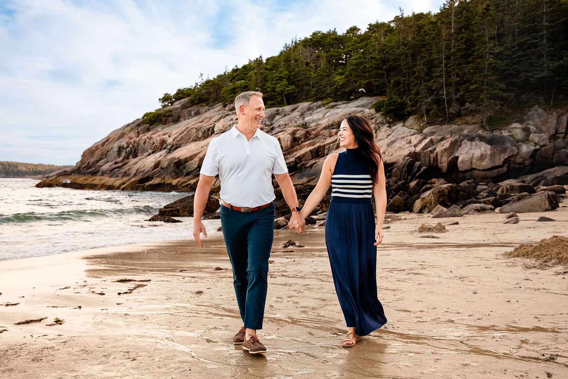 maine family photography daehler 10 A man and woman laugh as they hold hands and walk during a family portrait session on Sand Beach in Acadia National Park near Bar Harbor, Maine.