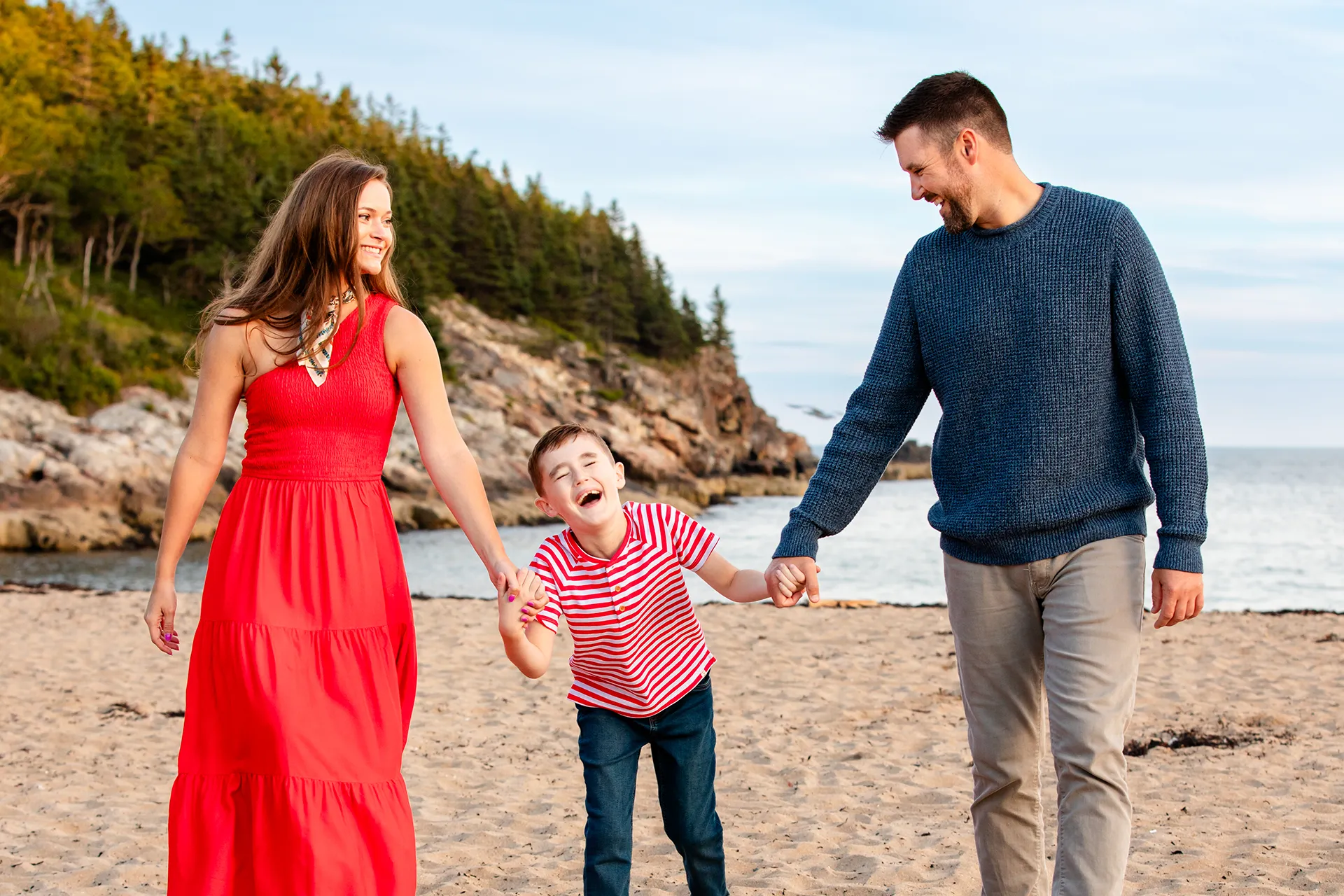 maine family photography daehler 16 A mom and dad hold a laughing boys hands during a family portrait session on Sand Beach in Acadia National Park near Bar Harbor, Maine.