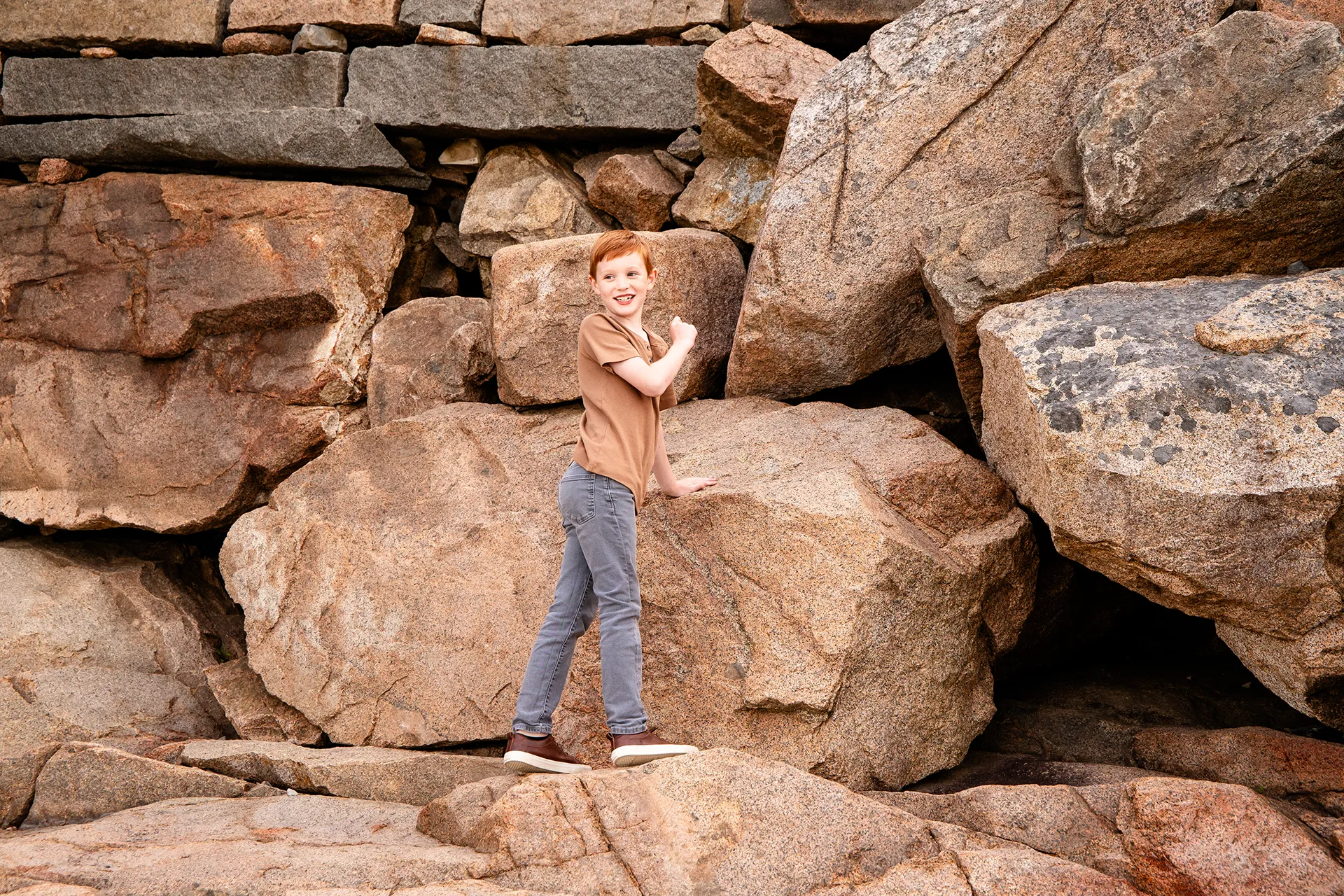 A boy climbs rocks during a family portrait session at Acadia National Park in Bar Harbor, Maine.