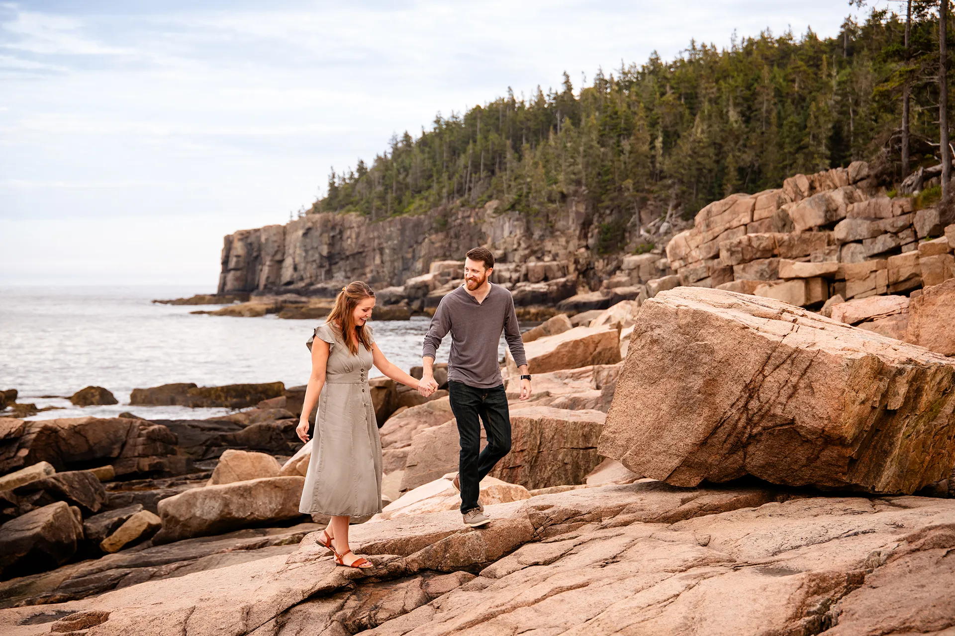 A man and woman hold hand as they walk during family portraits at Acadia National Park in Bar Harbor, Maine.