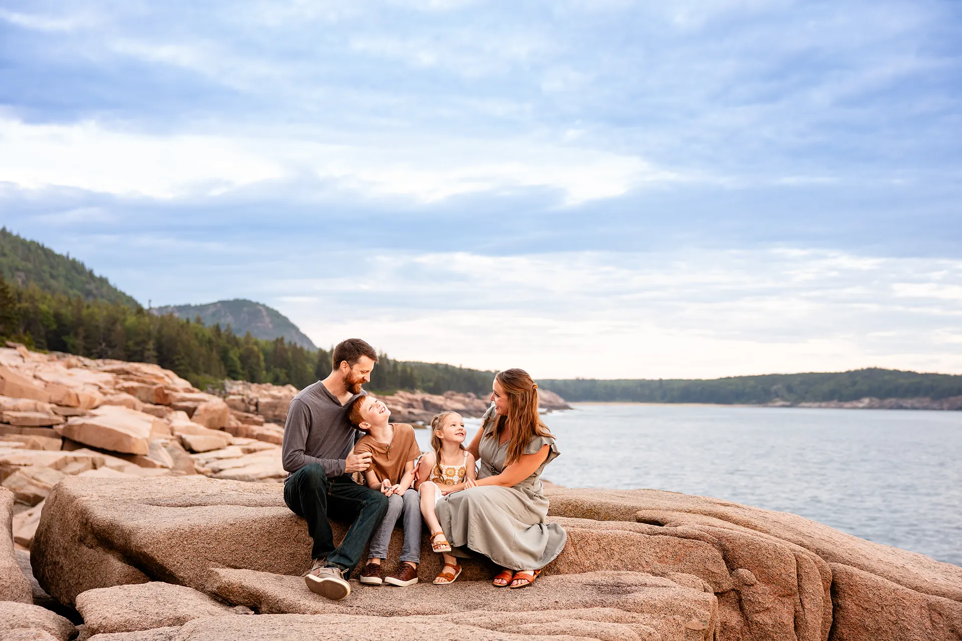 A family sits and snuggles in front of Beehive Mountain during family portraits at Acadia National Park in Bar Harbor, Maine.