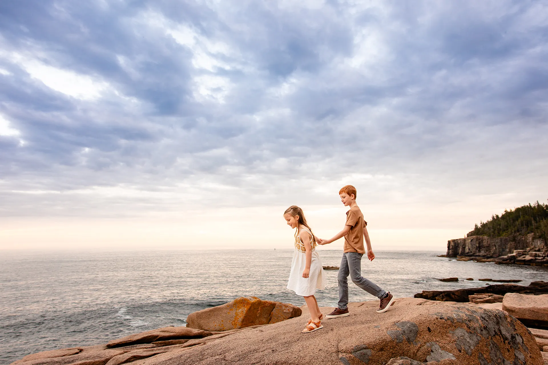 A brother and sister told hands as they walk along a rocky coastline near Otter Cliff at Acadia National Park in Bar Harbor, Maine.
