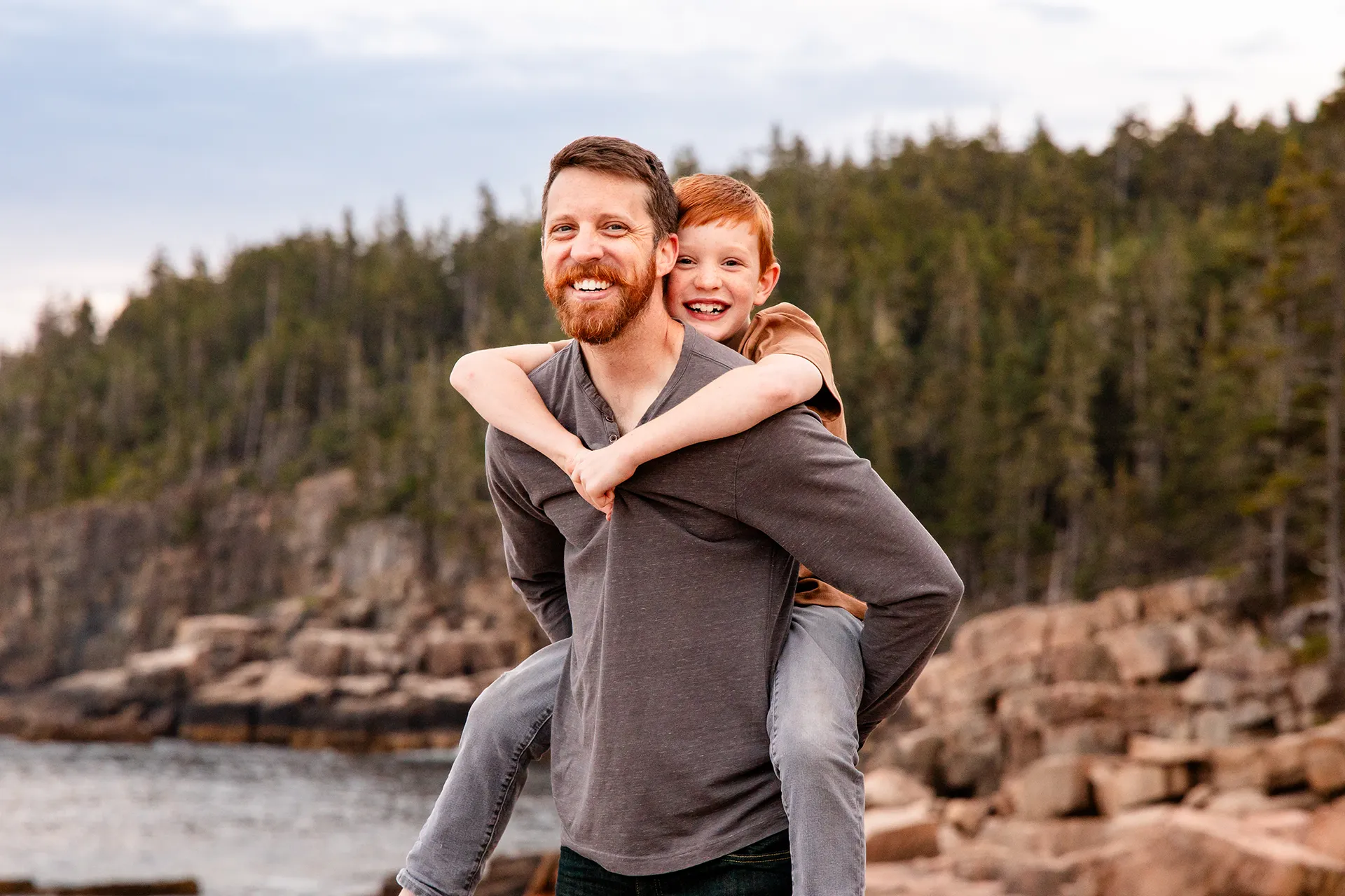 A dad gives his son a piggy back ride during family portraits at Acadia National Park in Bar Harbor, Maine.
