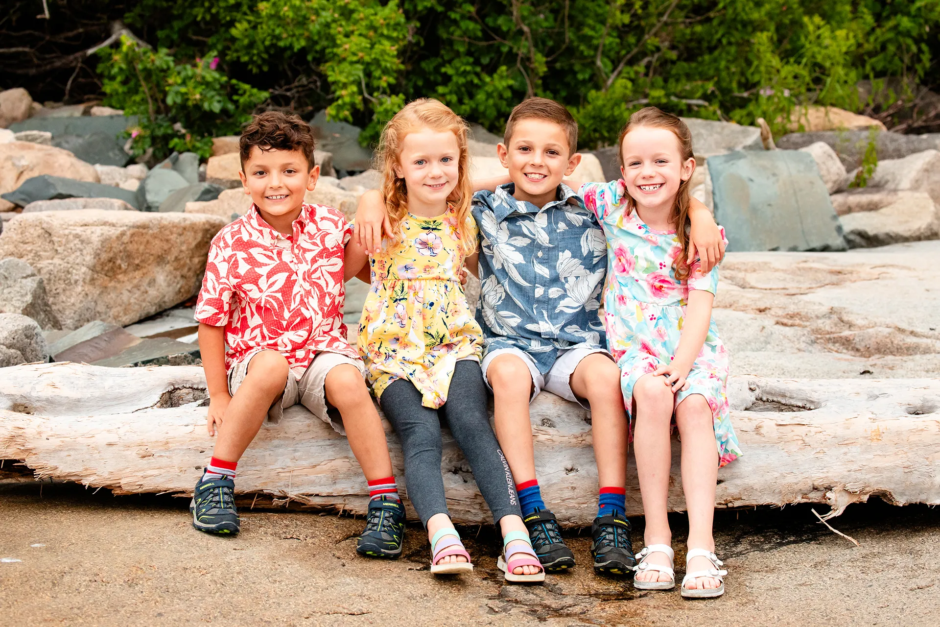 Children wearing bright colored clothing sit and pose for portraits at Grindstone Point in Winter Harbor, Maine.