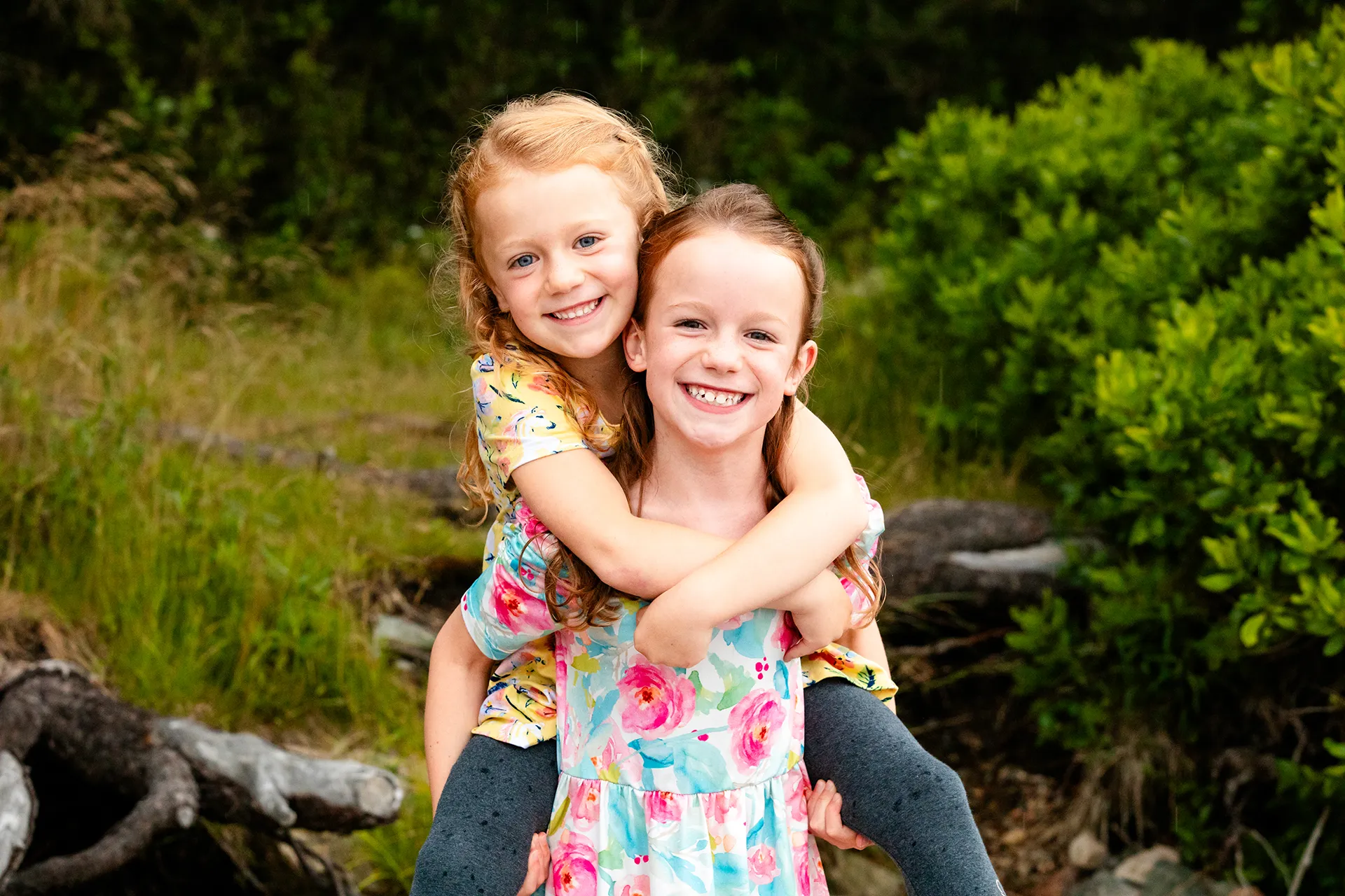 A girl gives her sister a piggyback ride during family portraits at Grindstone Point in Winter Harbor, Maine.