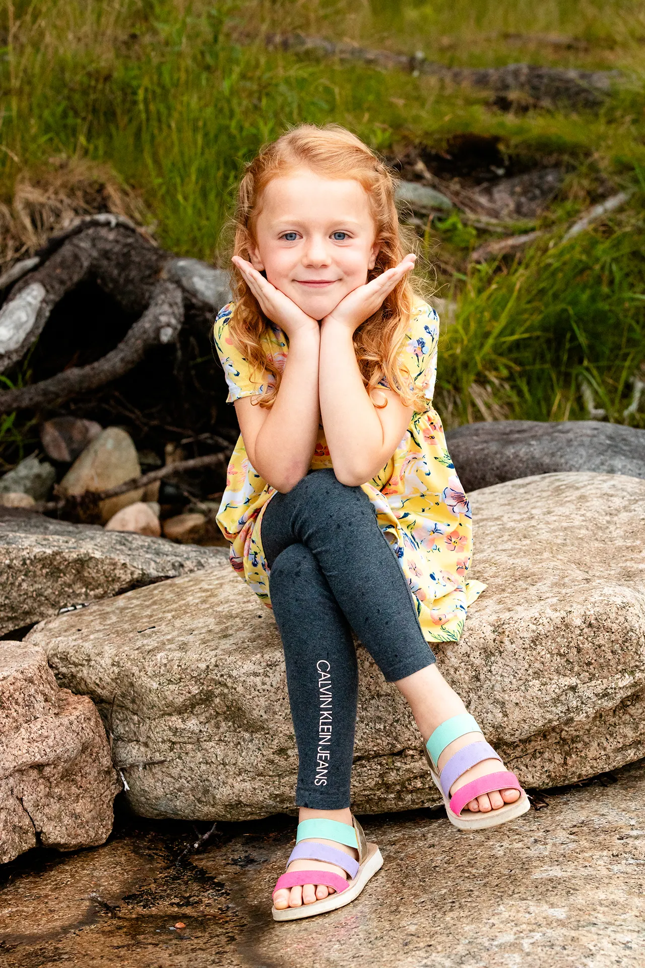 A girl sits and poses for portraits at Grindstone Point in Winter Harbor, Maine during a family portrait session.