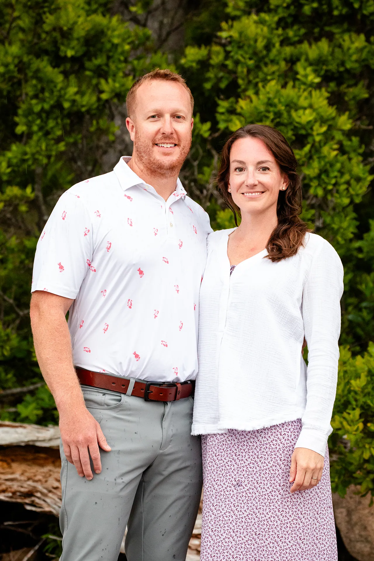 A couple smile and pose with their arms around each other during a family portrait session at Grindstone Point in Winter Harbor, Maine.