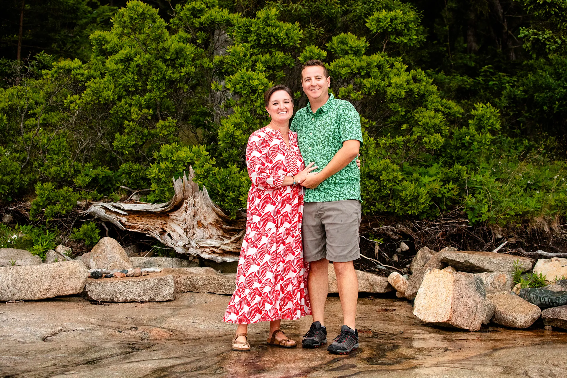 A man and woman smile and pose during family portraits Grindstone Point in Winter Harbor, Maine.