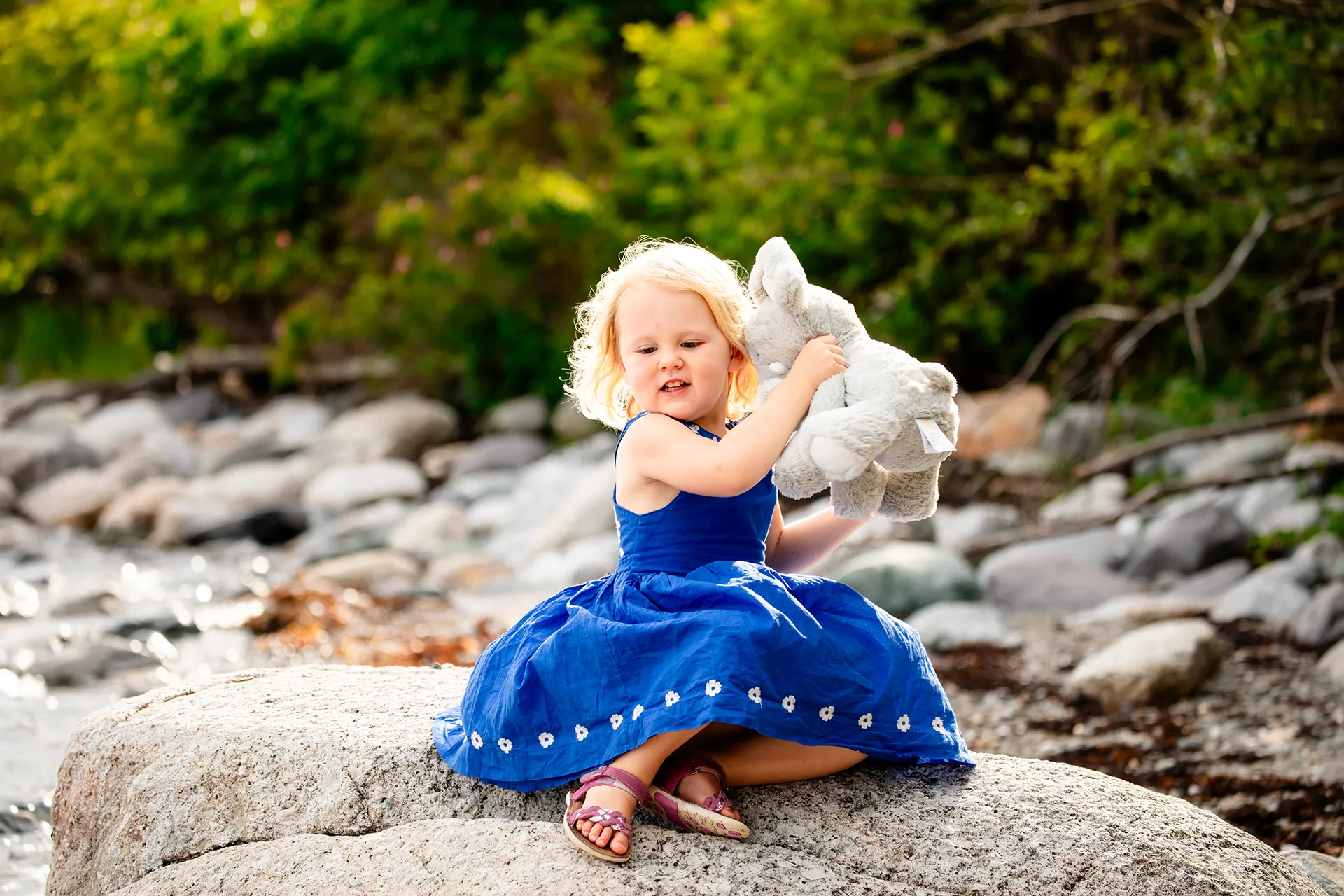 maine family photography moldawer mandsager 08 A young girl sits on a rock and plays with her toy during a family portrait session in Lamoine, Maine.