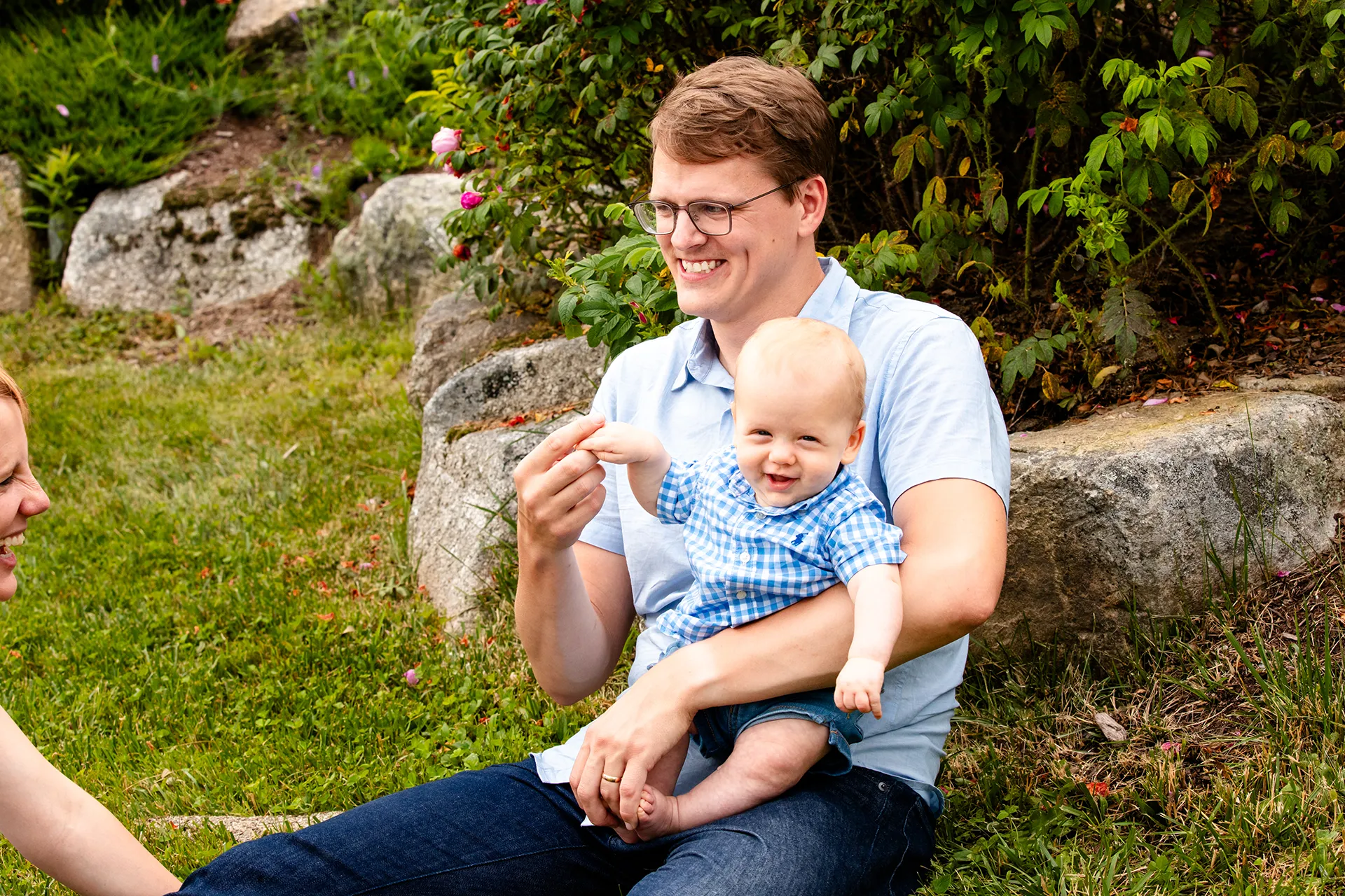 maine family photography moldawer mandsager 18 A young boy smiles as he sits in his dads lap during a family portrait session in Lamoine, Maine.