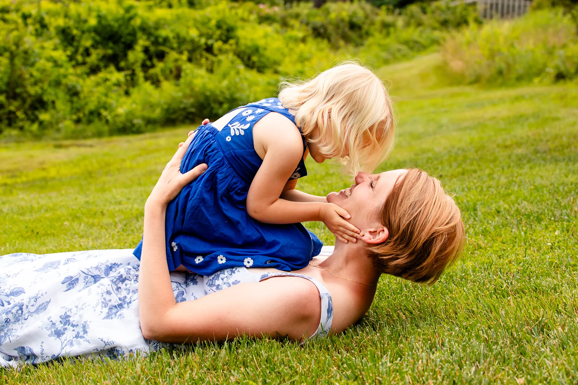 maine family photography moldawer mandsager 19 A young girl sits on her mom as they lay in the grass during a family portrait session in Lamoine, Maine.