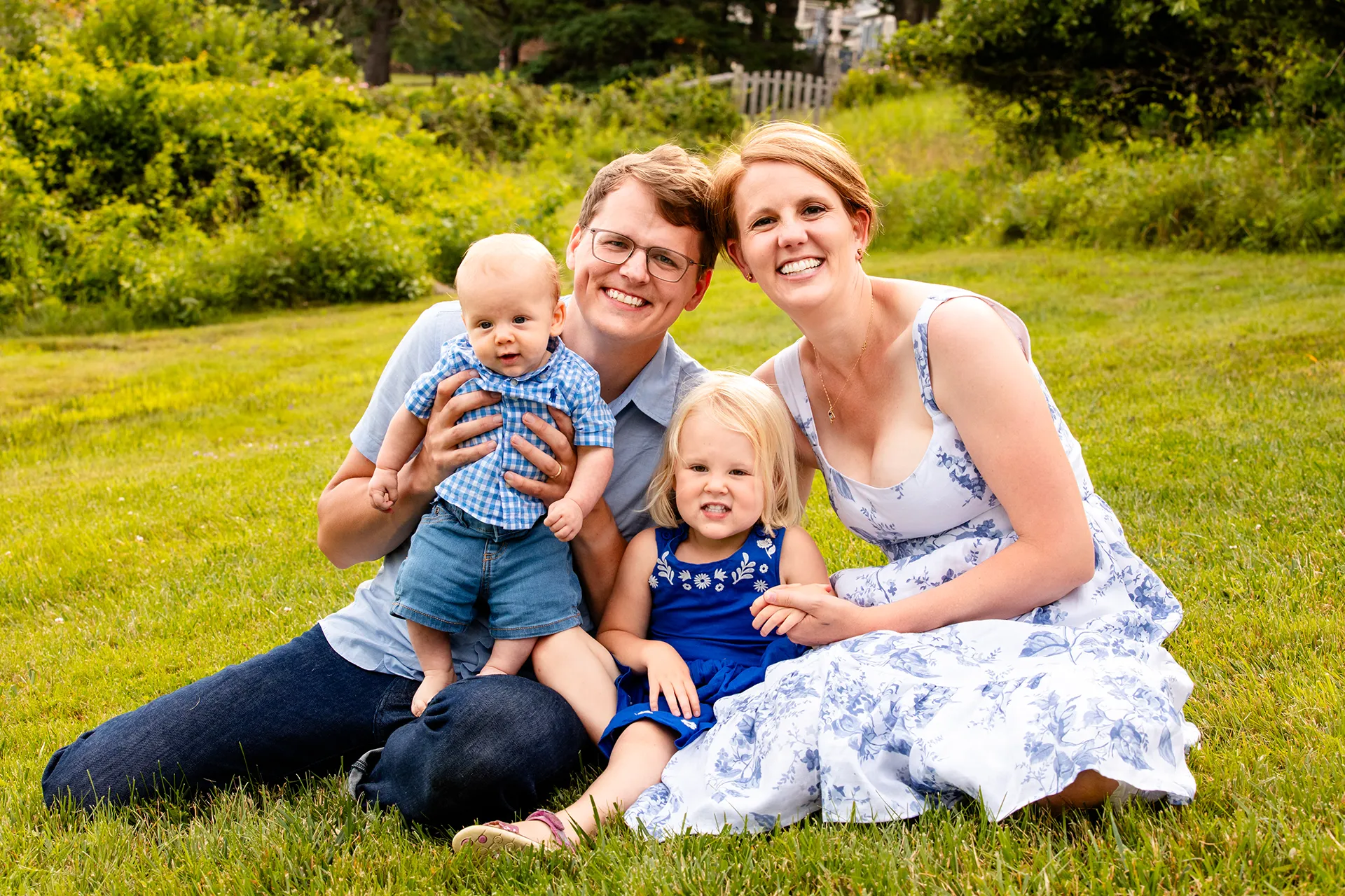 maine family photography moldawer mandsager 24 A family of four sits and poses in the grass during a family portrait session in Lamoine, Maine.