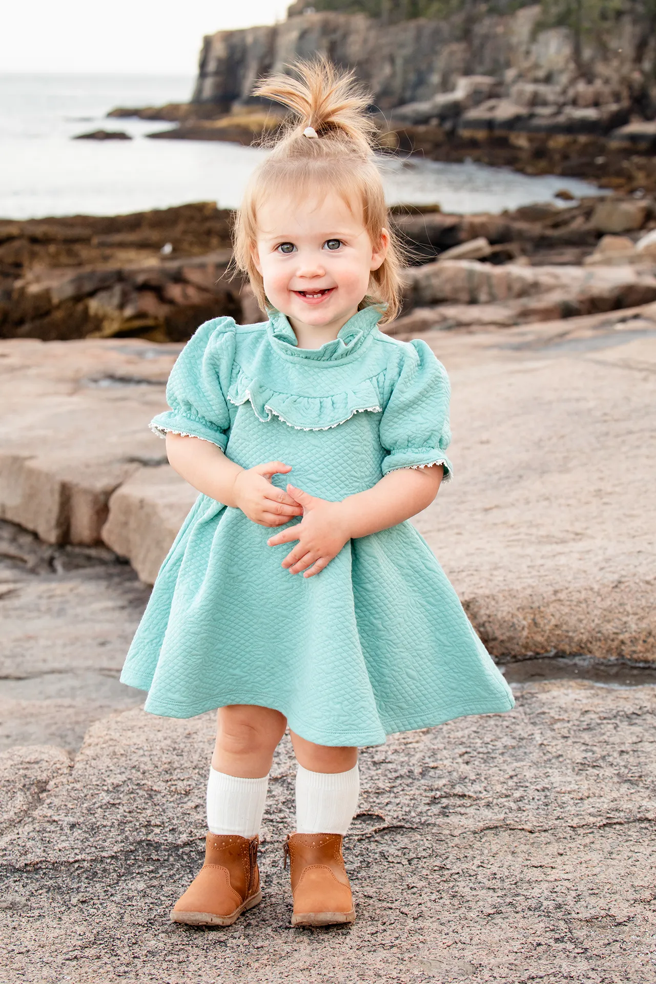 maine family photography myer 02 A young girl smiles as she poses during a family portrait session near Otter Cliff in Acadia National Park.