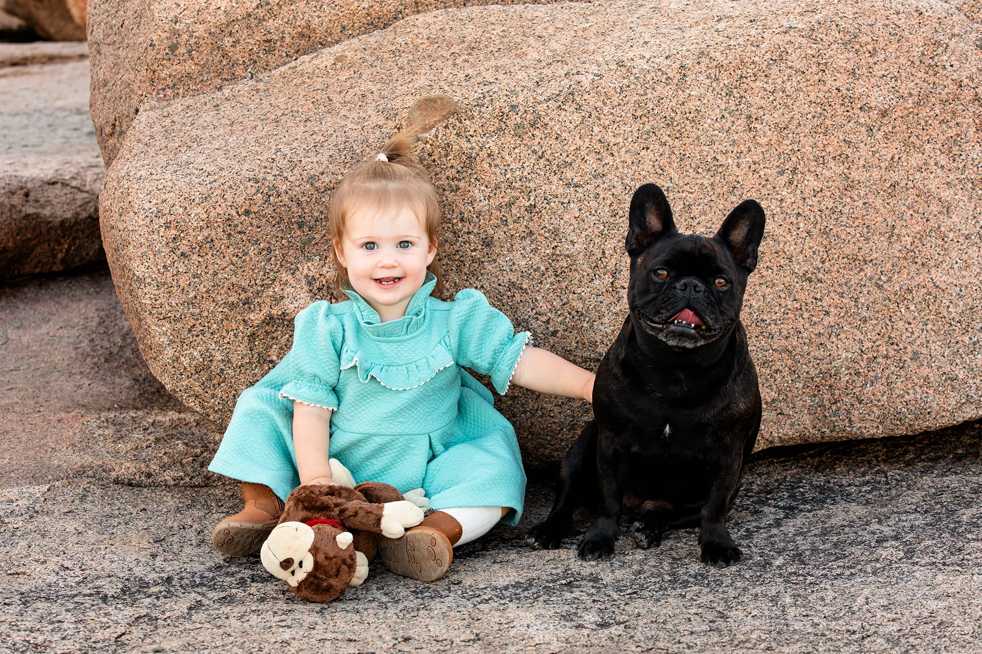 maine family photography myer 03 A young girl smiles and sits with a black dog during a family portrait session near the Ocean Path Trail in Acadia National Park.