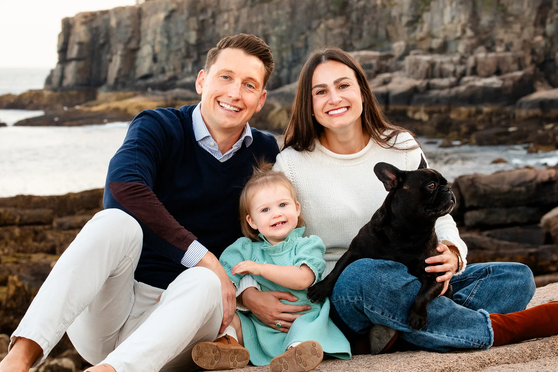 maine family photography myer 06 A family sits in front of Otter Cliff during a family portrait session near the Ocean Path Trail in Acadia National Park.