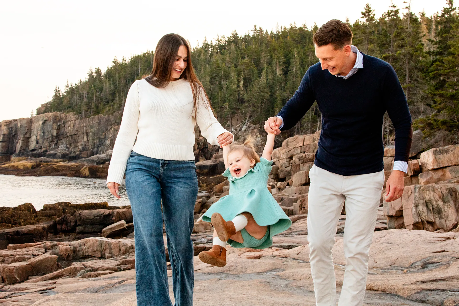 maine family photography myer 10 A mom and dad swing their young daughter during a family portrait session near the Ocean Path Trail in Acadia National Park.