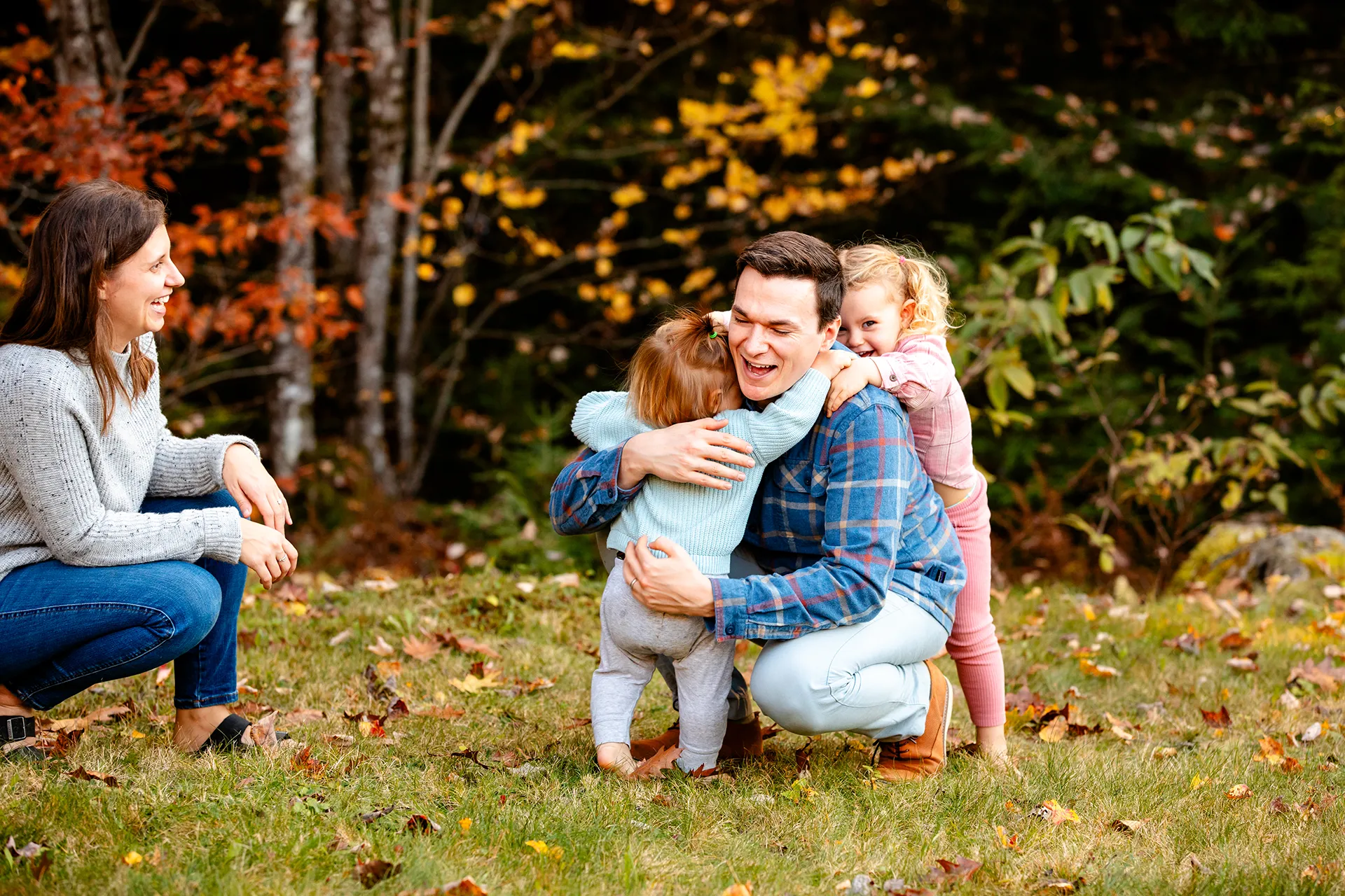 maine family photography sleeper wolland 16 A dad is hugged by his daughters as a mom laughs during a fall family portrait session near Bangor, Maine.
