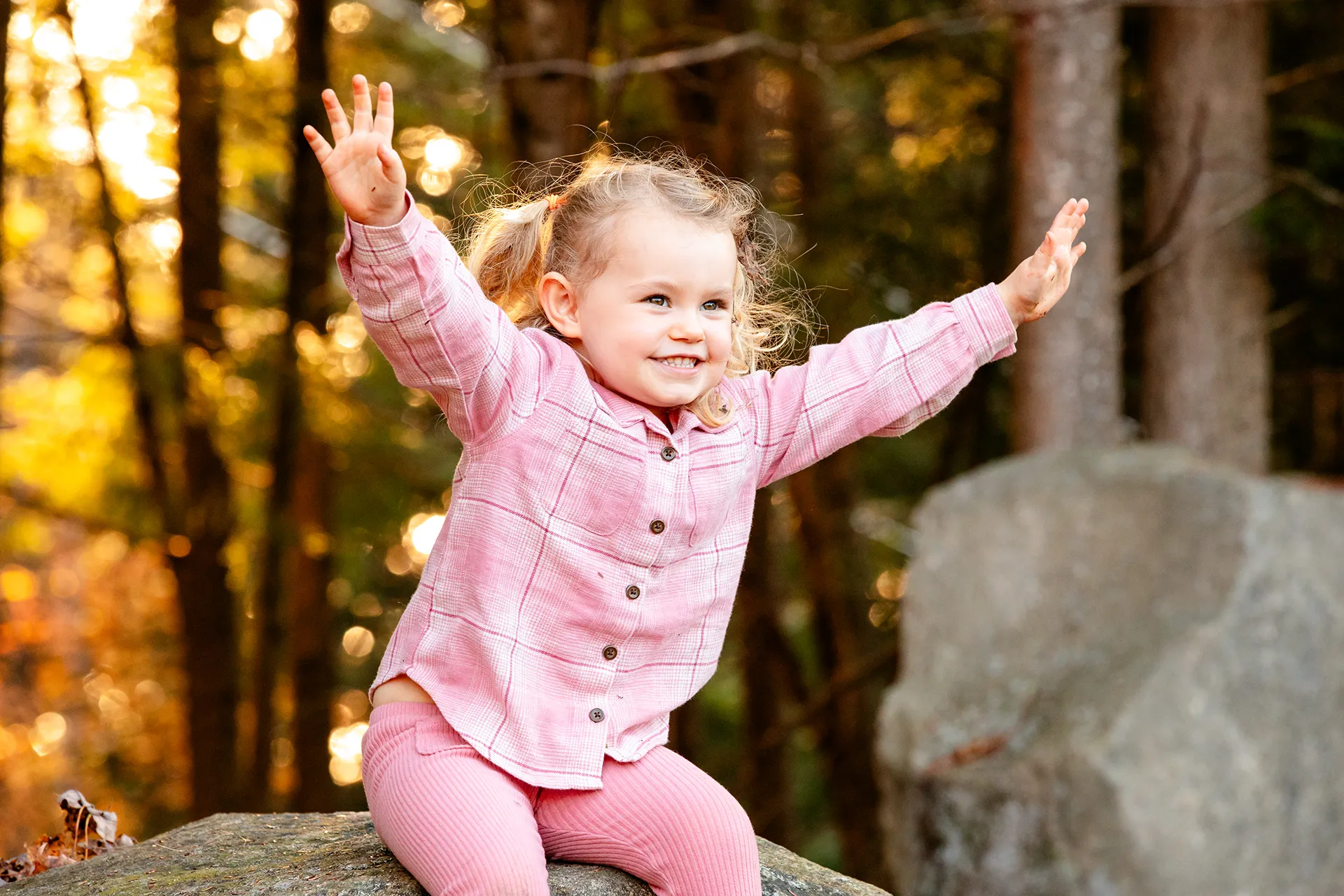 maine family photography sleeper wolland 20 A girl smiles as she sits on a rock during a fall family portrait session near Bangor, Maine.
